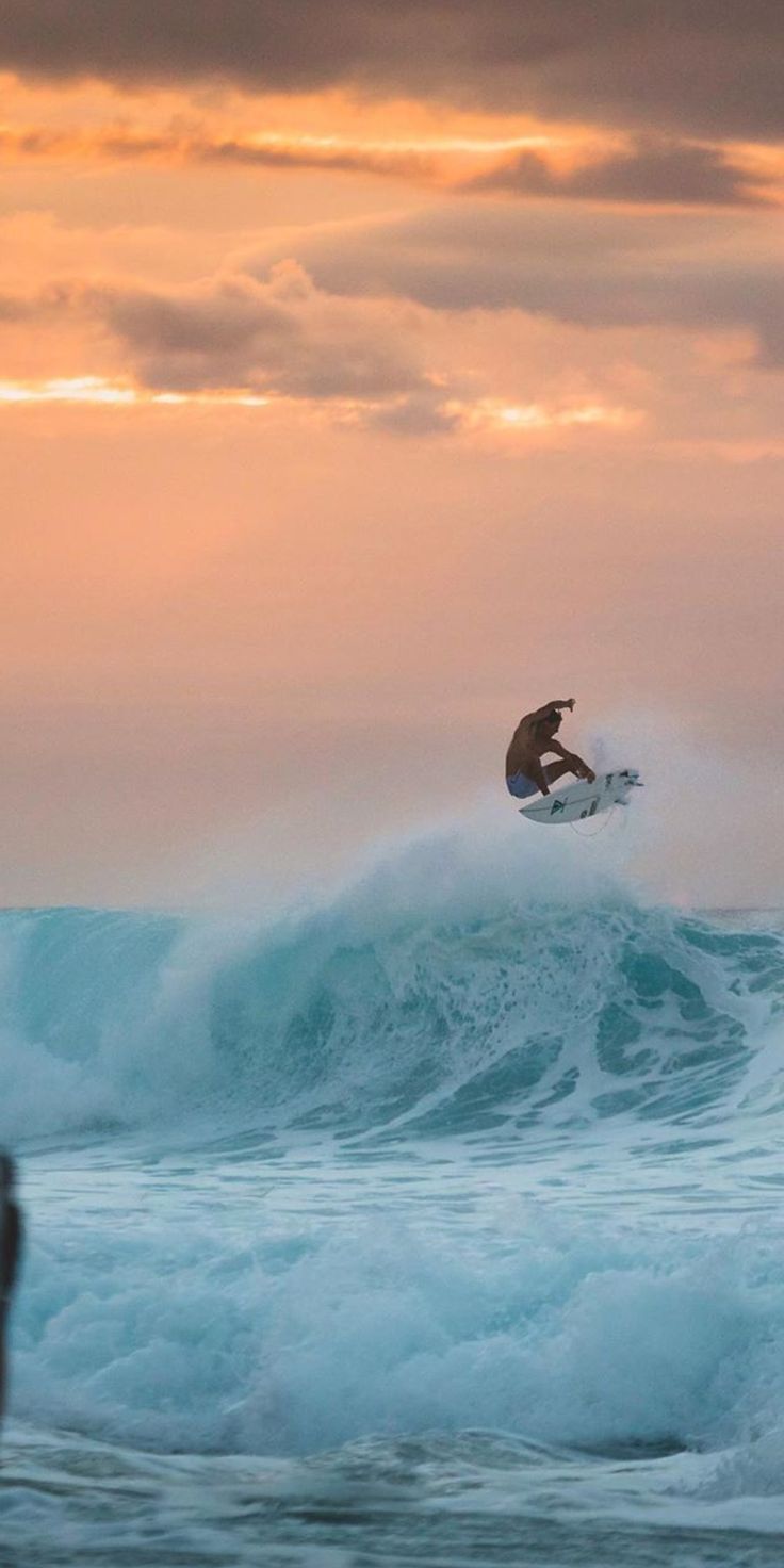 A surfer rides a wave during sunset - Surf