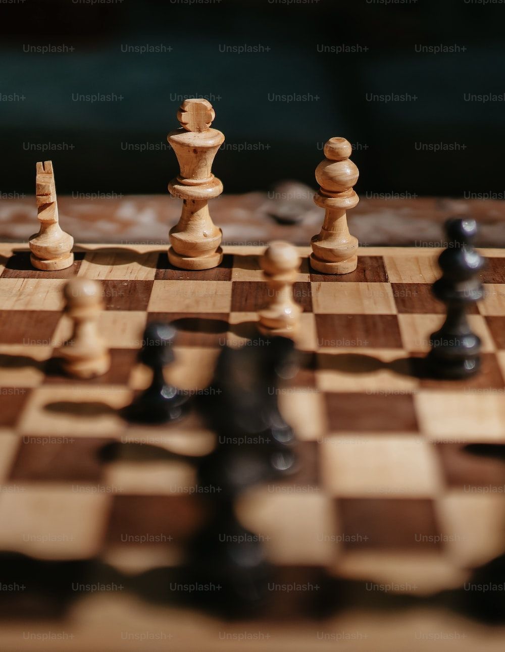 Chess pieces on a board with a close up of the king and queen. - Chess
