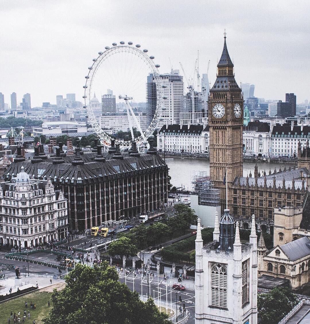 A city with a large clock tower, river, and a Ferris wheel. - London