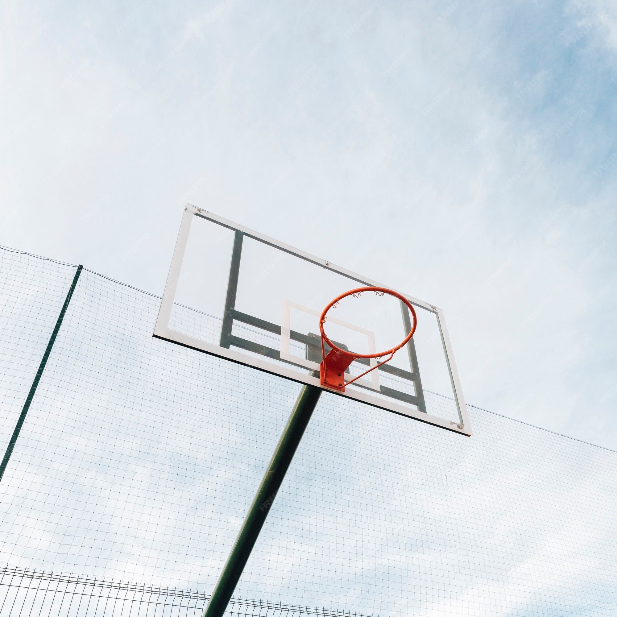 Free Photo. Basketball hoop and net on fence with sky view