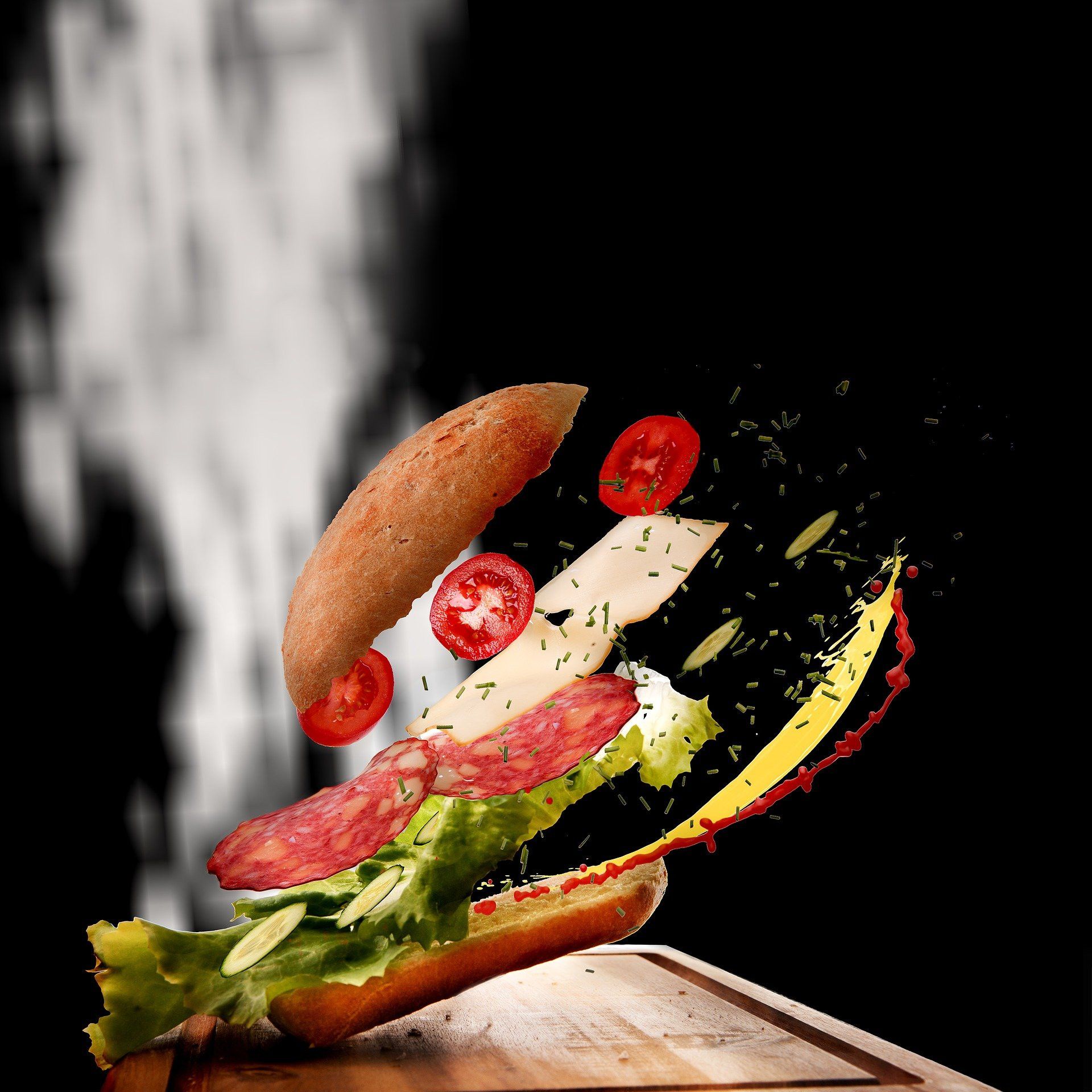 A delicious burger with flying ingredients on a black background - Food