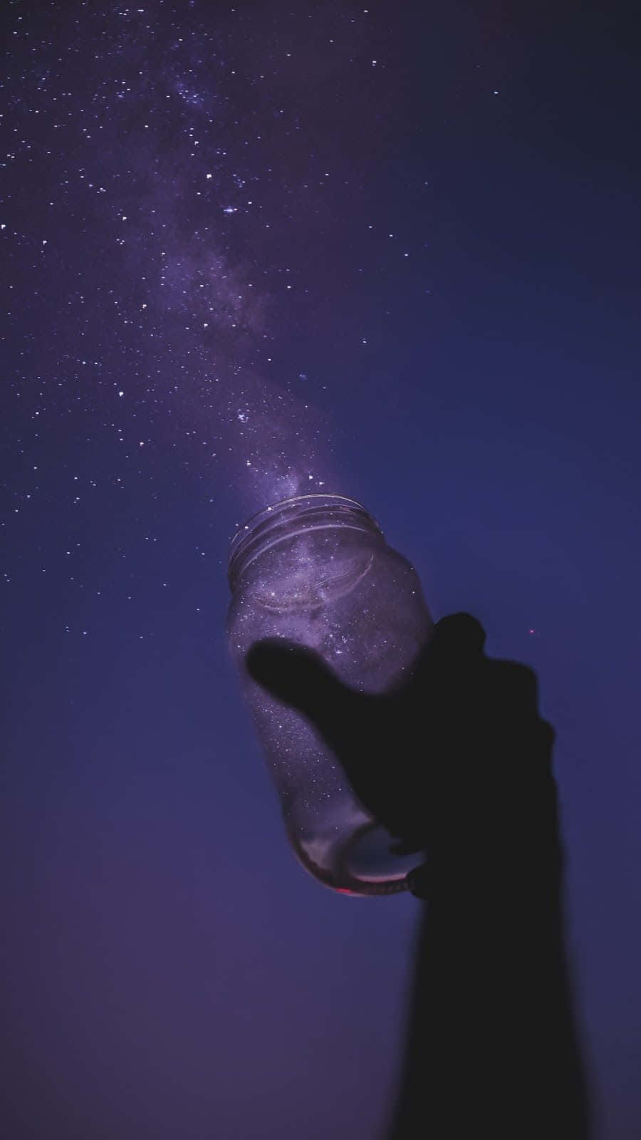 A hand holding a jar with stars in it. - Stars
