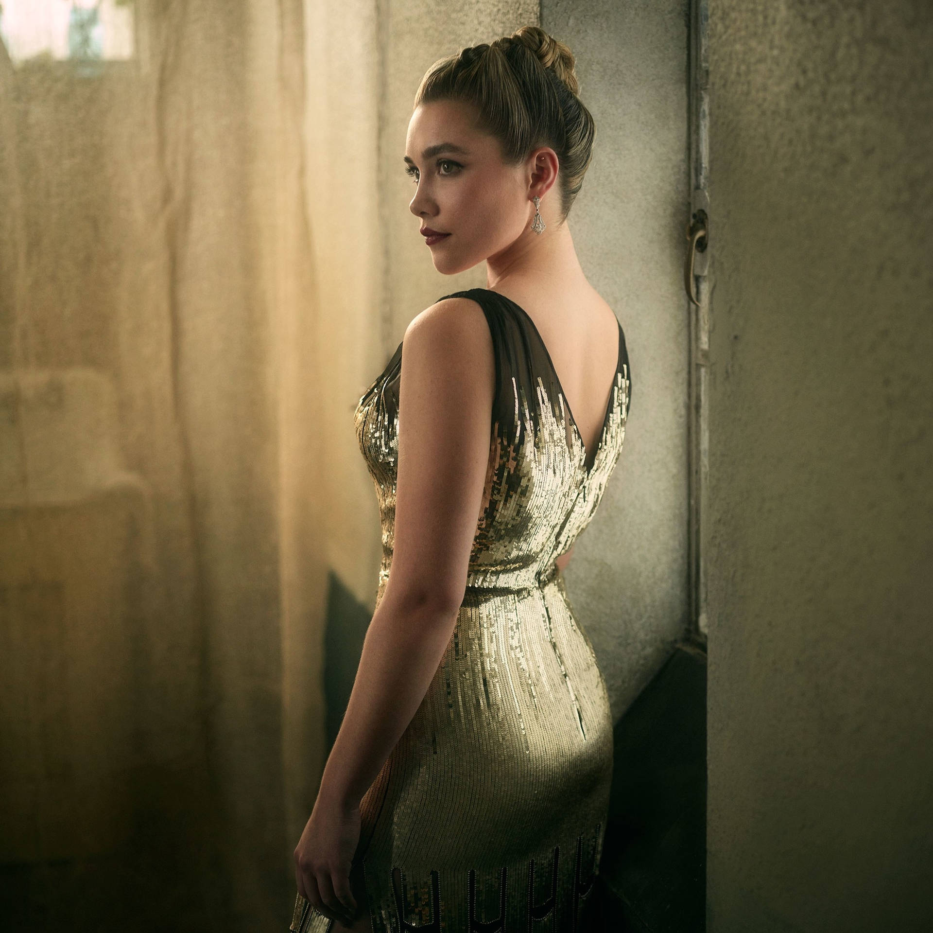 A woman in a gold dress standing in a doorway - Florence Pugh