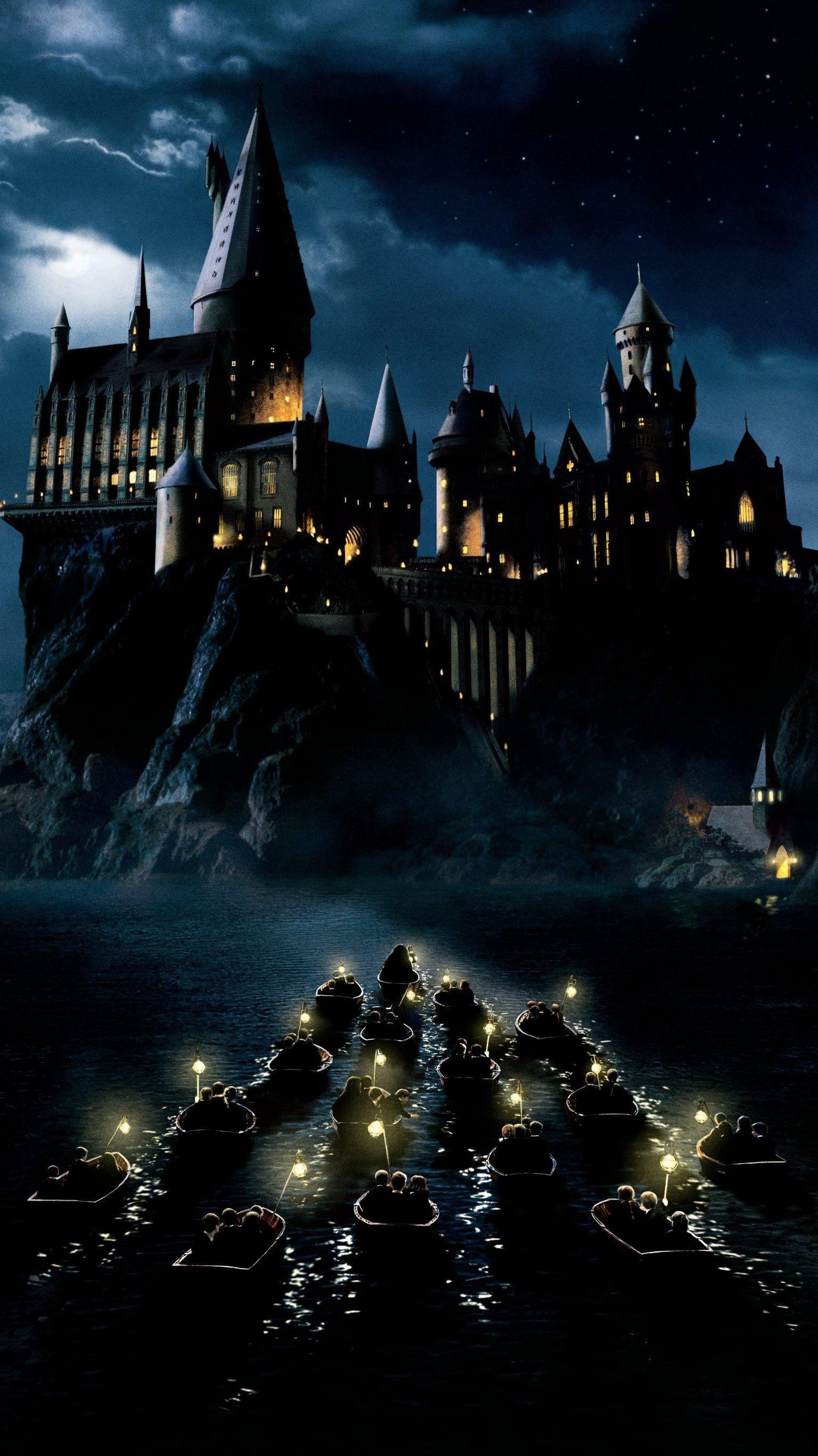 A castle with boats and lights on the water - Harry Potter