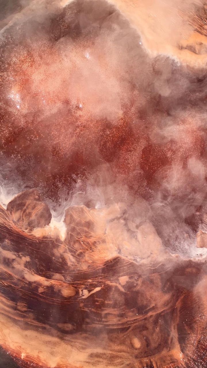 A close up of a bowl with a brown and white marbled pattern and steam rising from it. - Venus