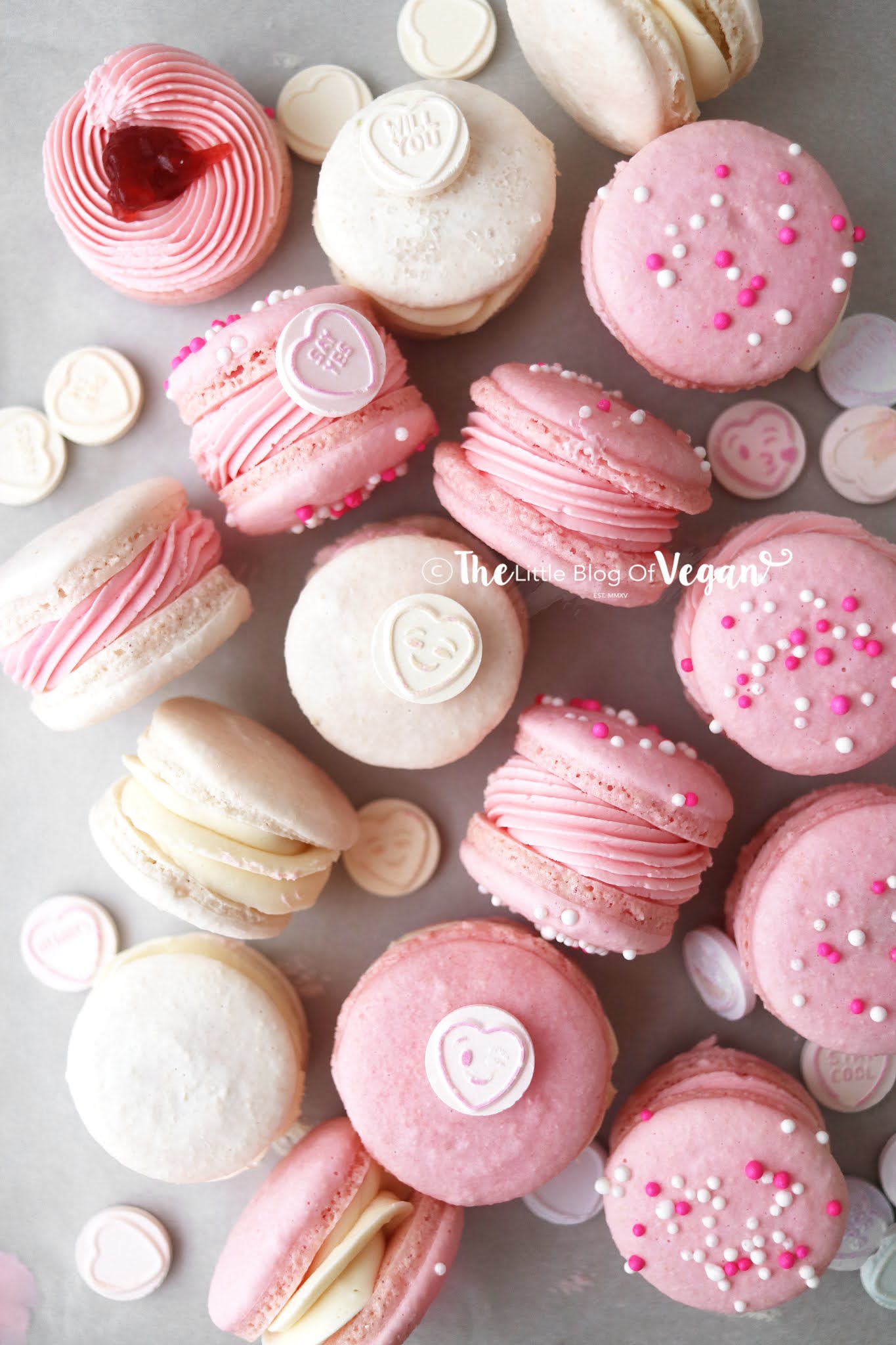 A plate of pink and white macarons with a heart on top. - Macarons