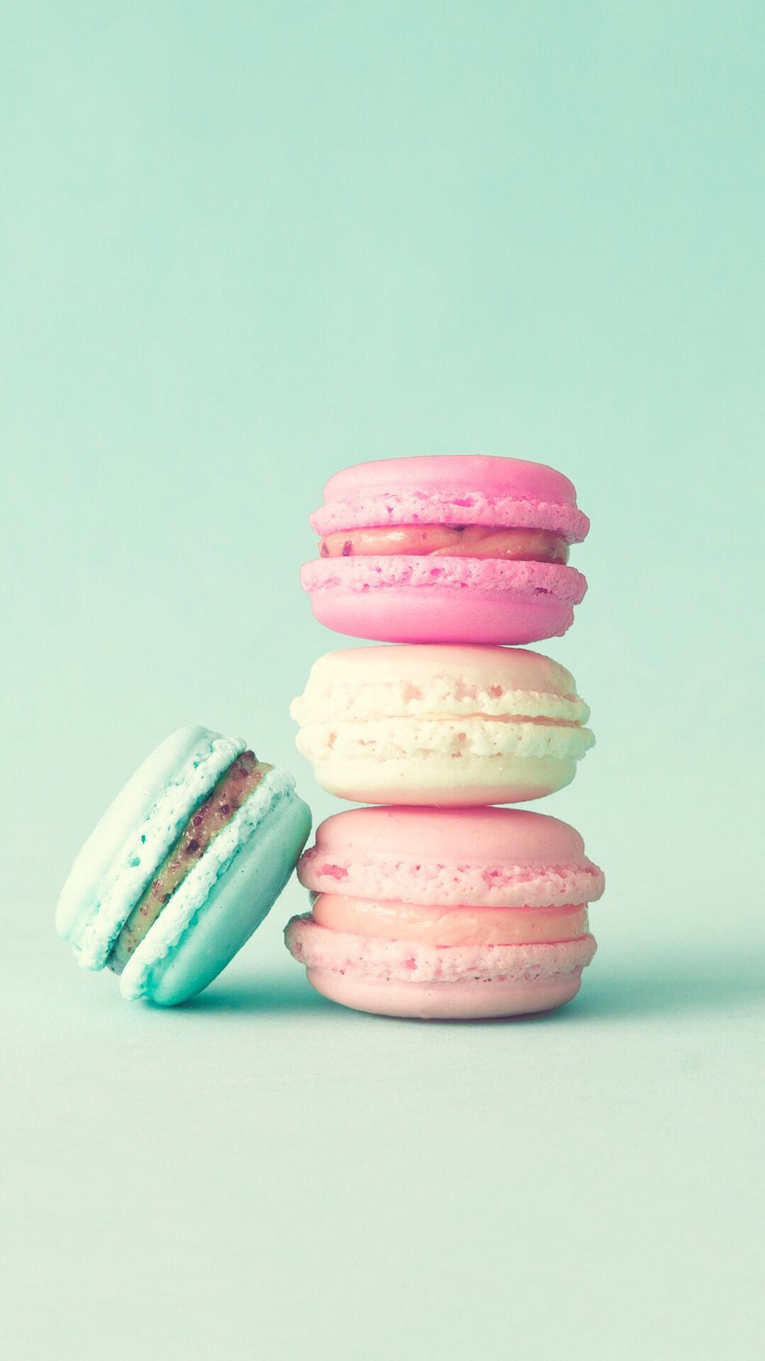 A stack of four colorful macarons on a blue background - Macarons