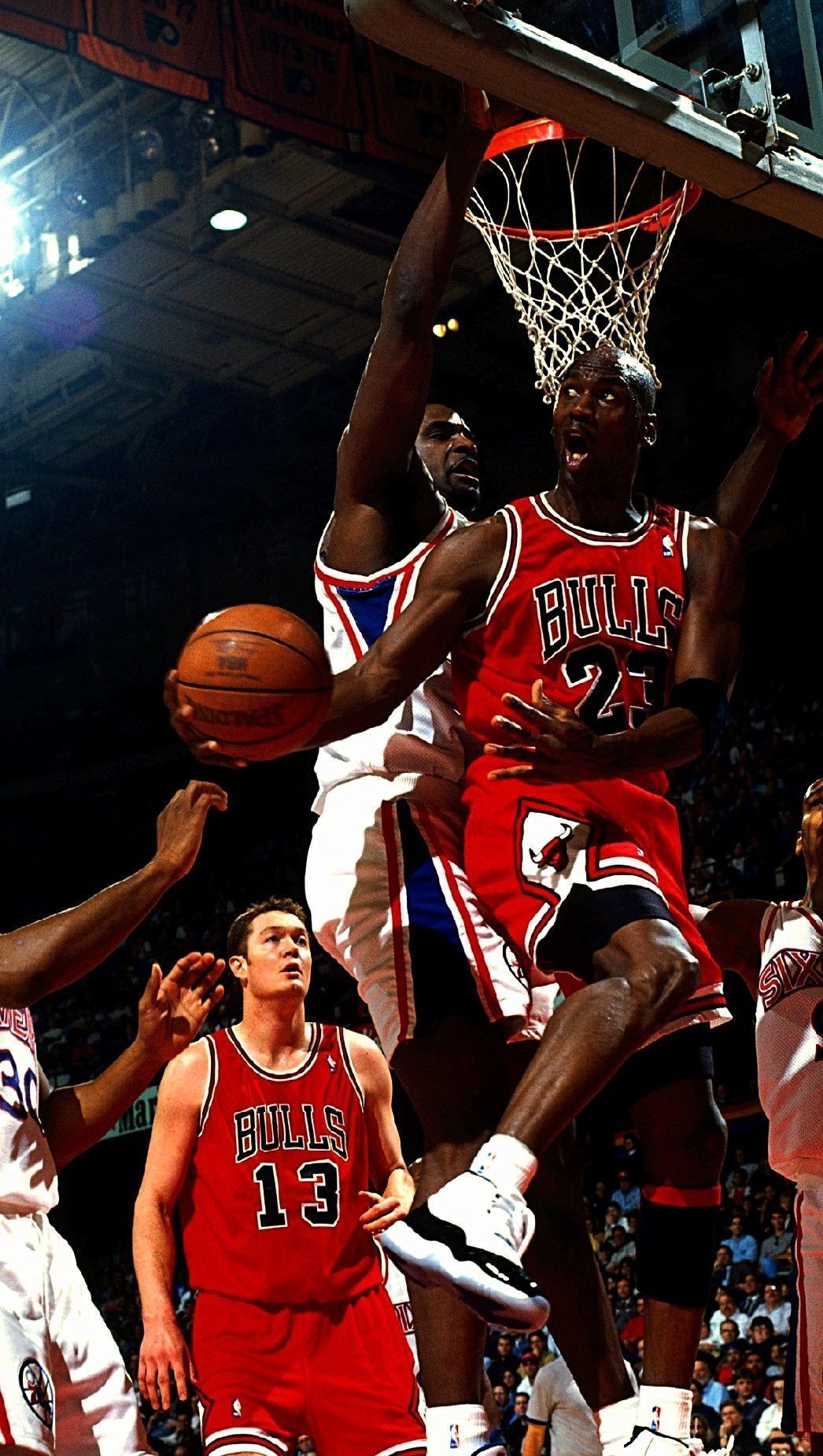 Jordan is in the air with the ball in his hand, attempting to pass the ball to teammate. - Michael Jordan