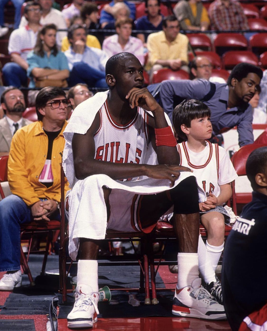 Michael Jordan sits on the bench with a young fan during a Bulls game. - Michael Jordan