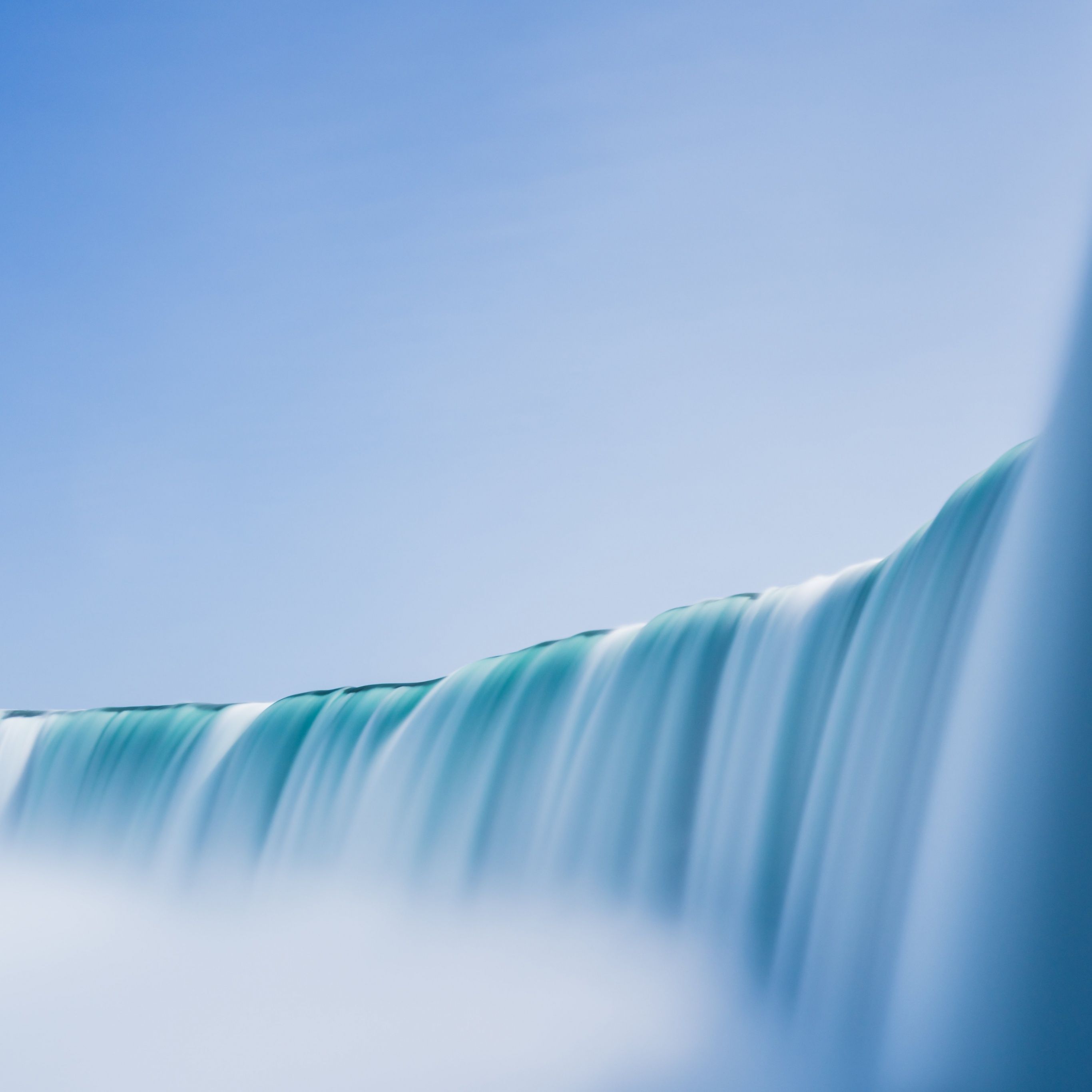 A close up of a waterfall with a blue sky in the background. - Waterfall