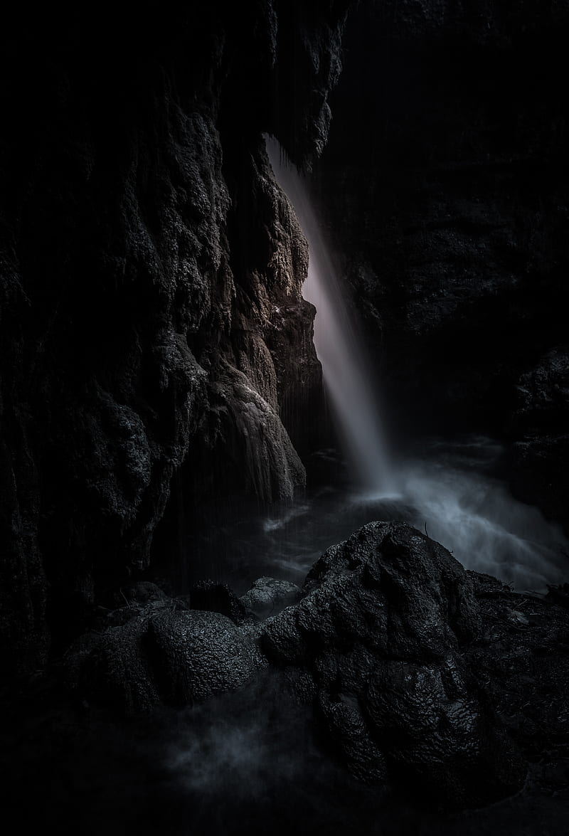 A waterfall flowing into a dark pool of water. - Waterfall