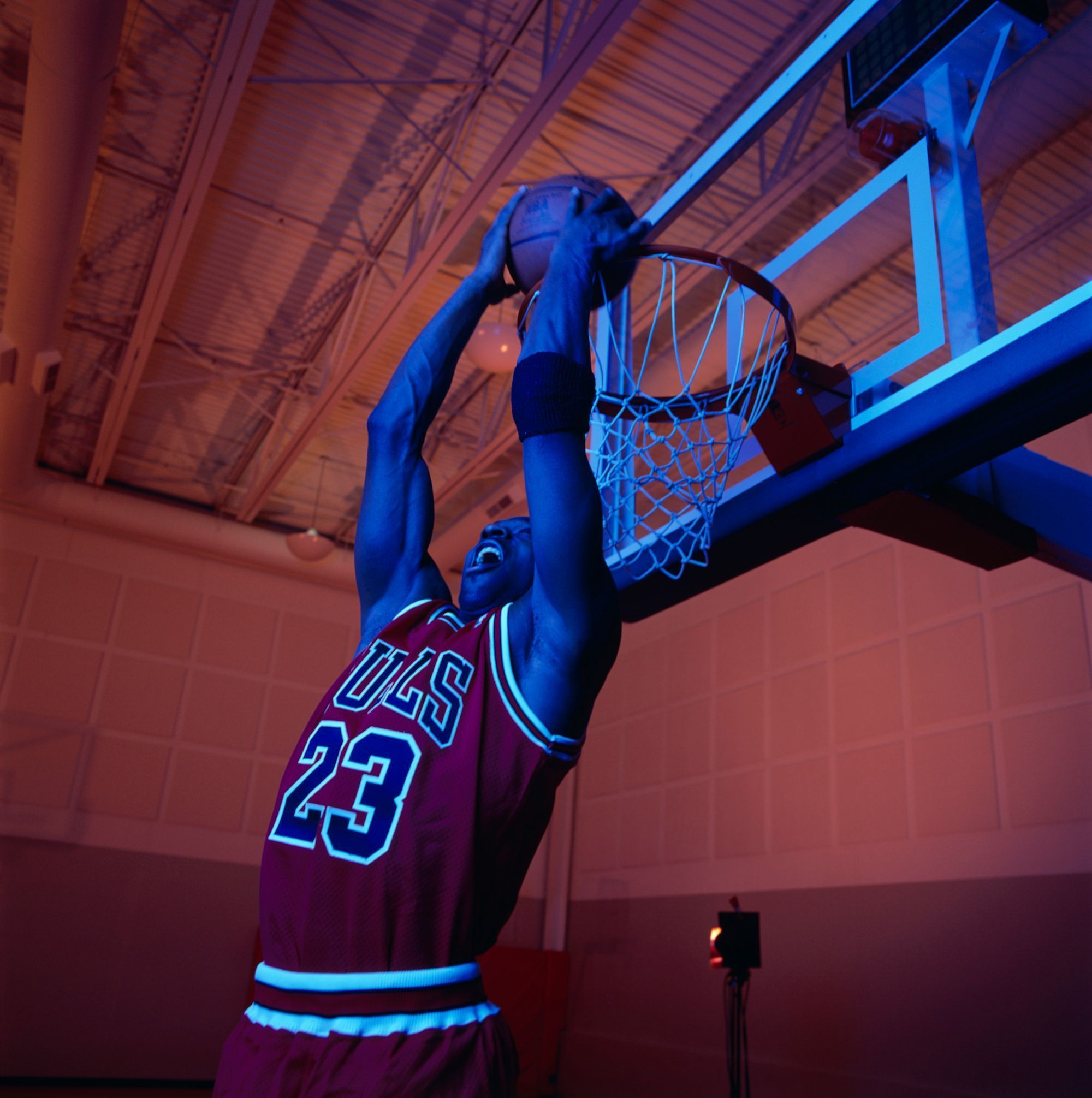 A man in a Bulls jersey is dunking a basketball through a hoop. - Michael Jordan