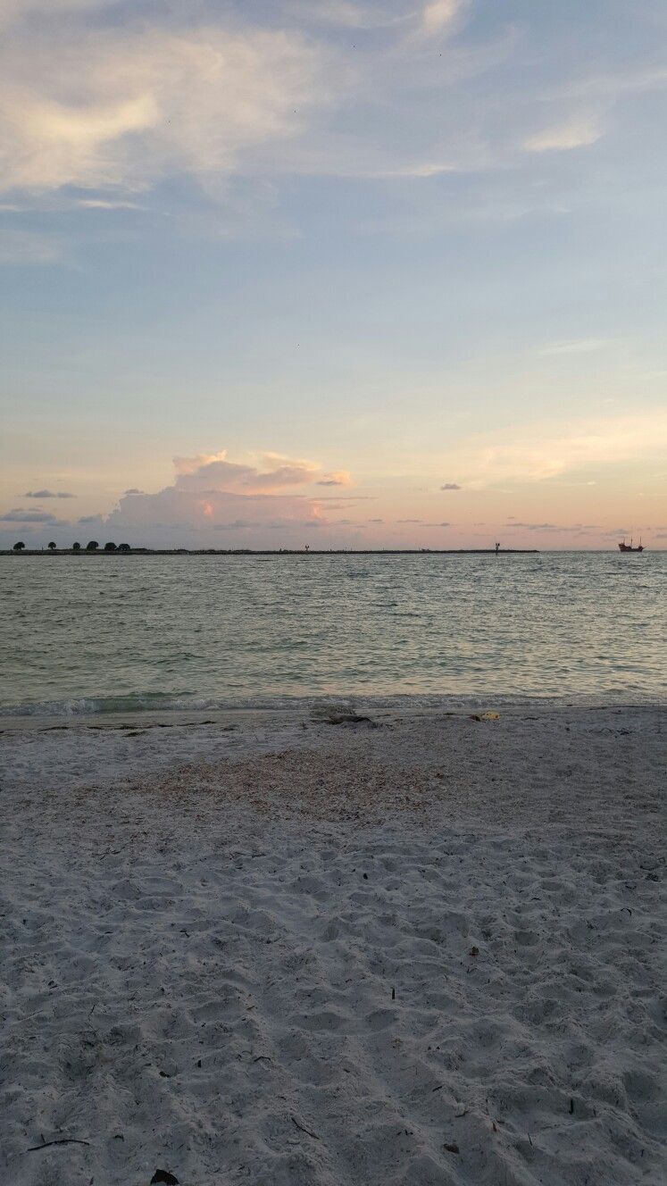 A serene beach with a sandy shore and a calm sea at dusk. - Florida