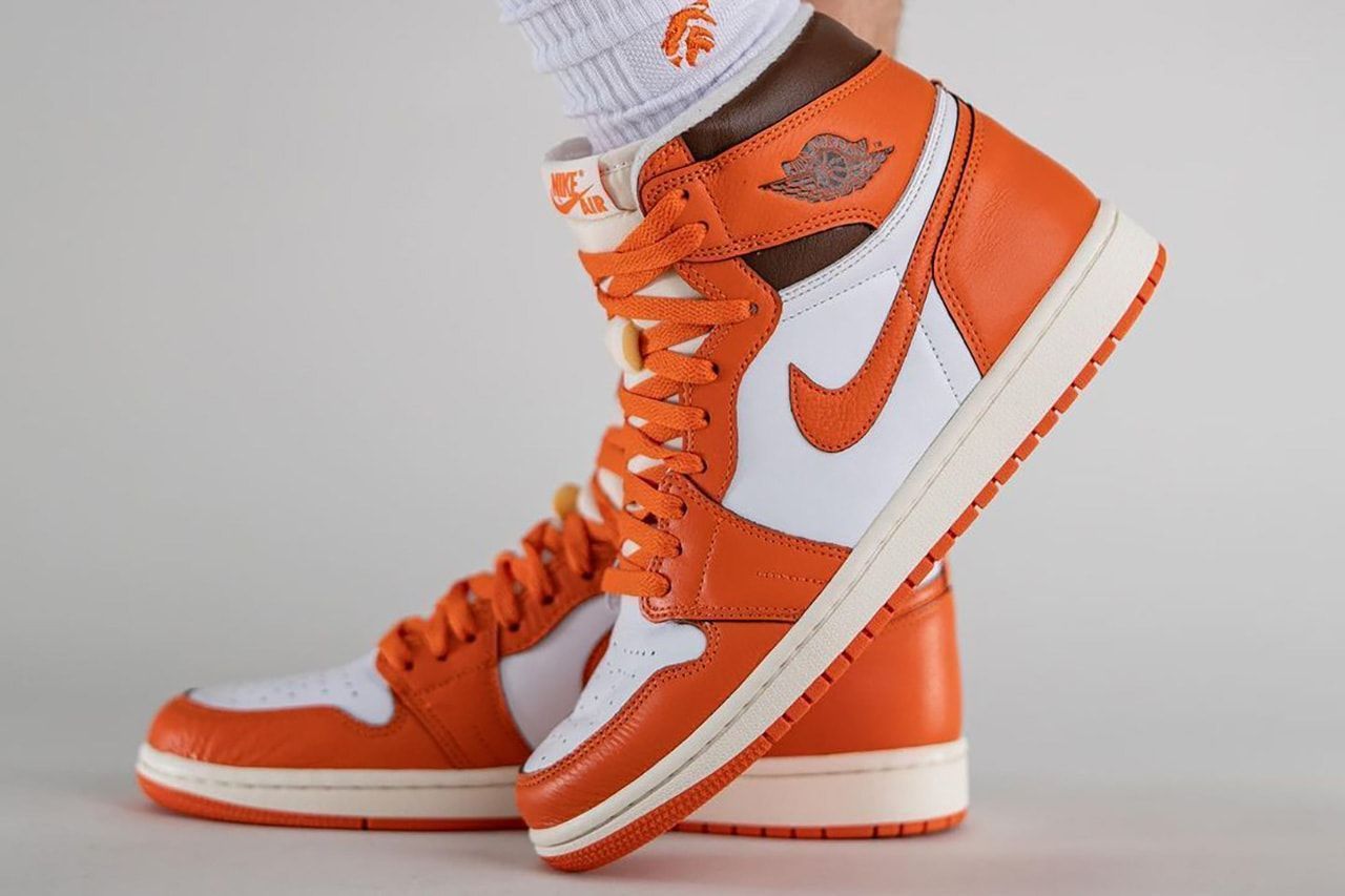 A person wearing orange and white sneakers - Air Jordan 1