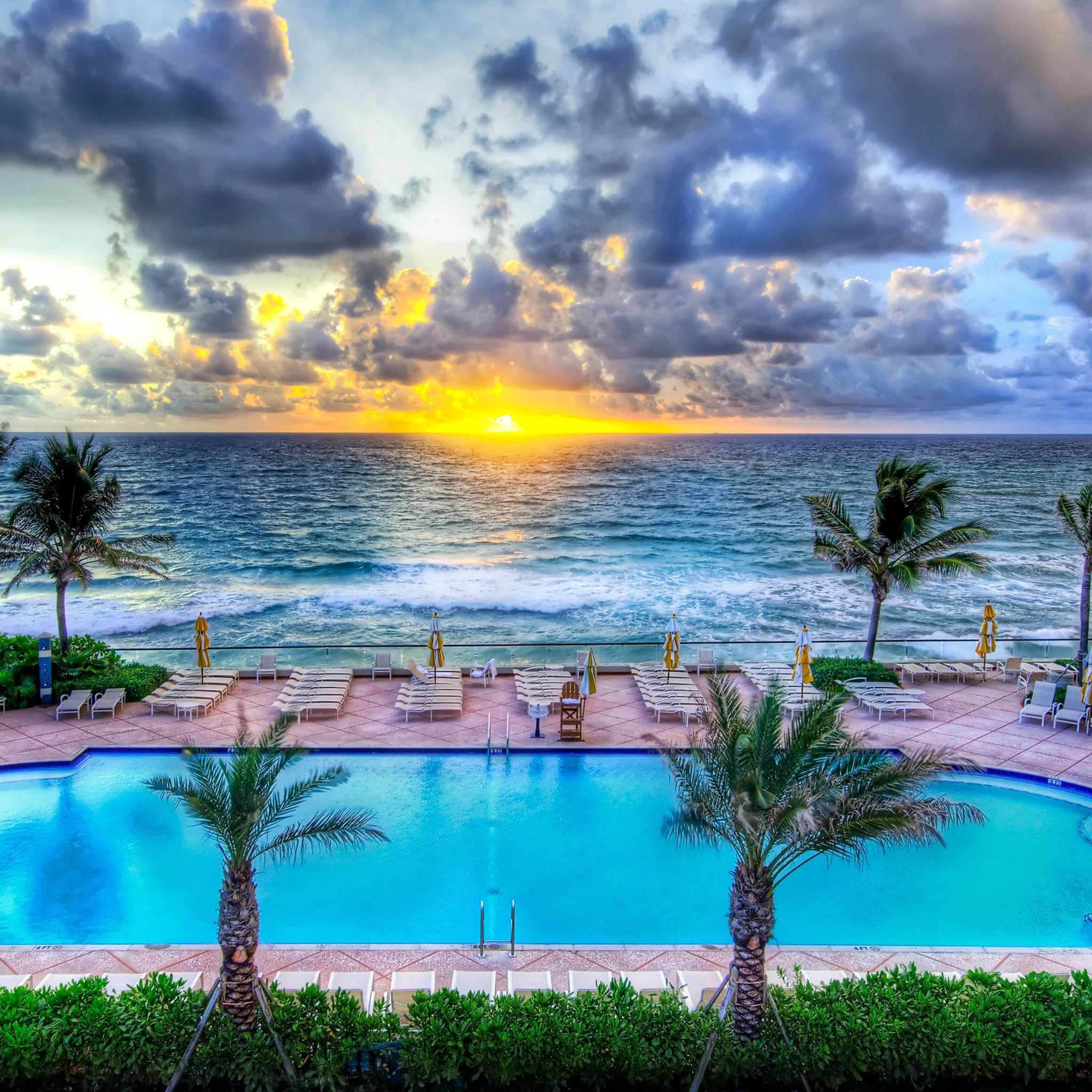 The sun sets over the ocean with a pool in the foreground. - Florida, swimming pool