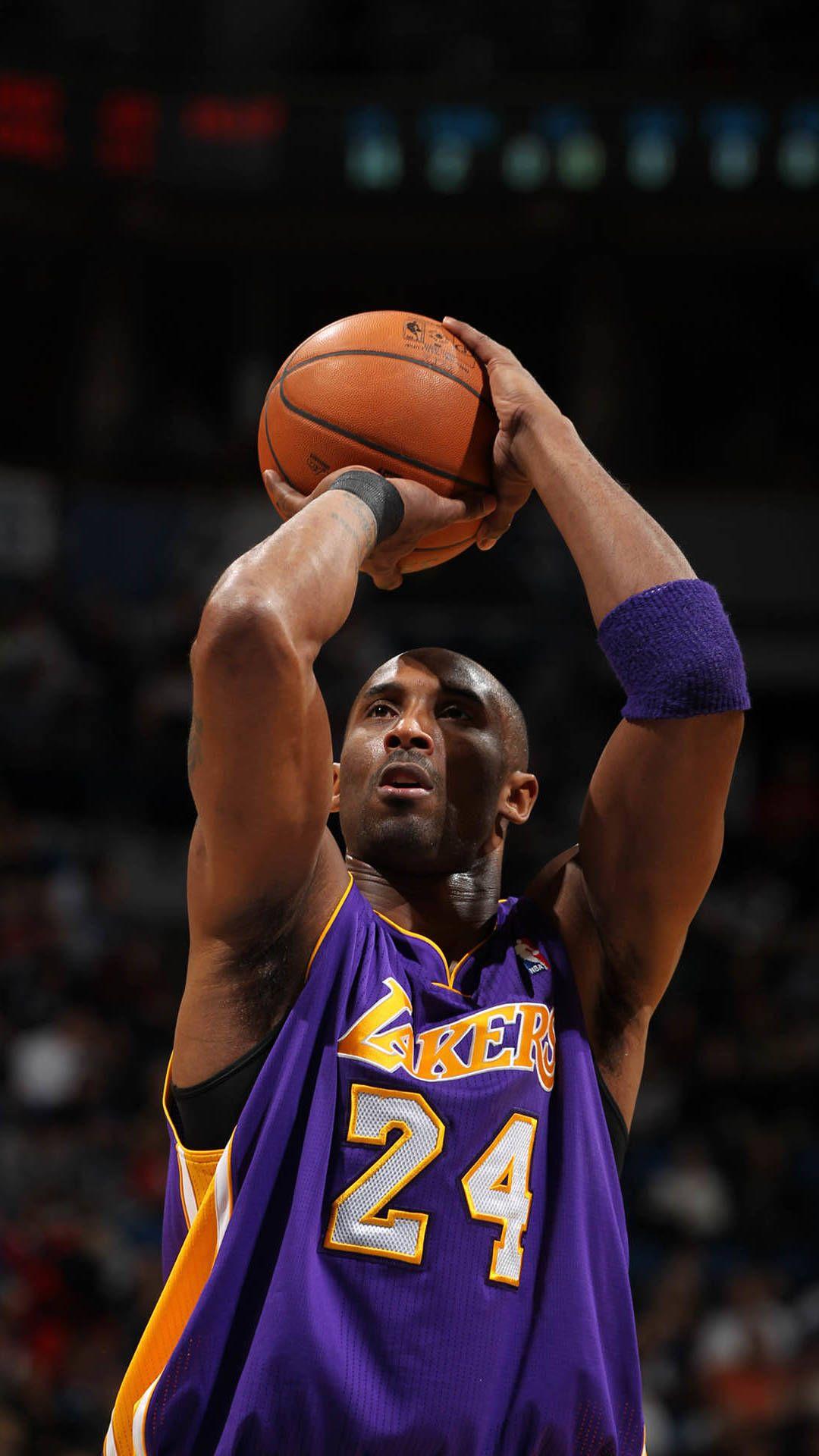 A man in purple and yellow basketball uniform holding up the ball - Kobe Bryant