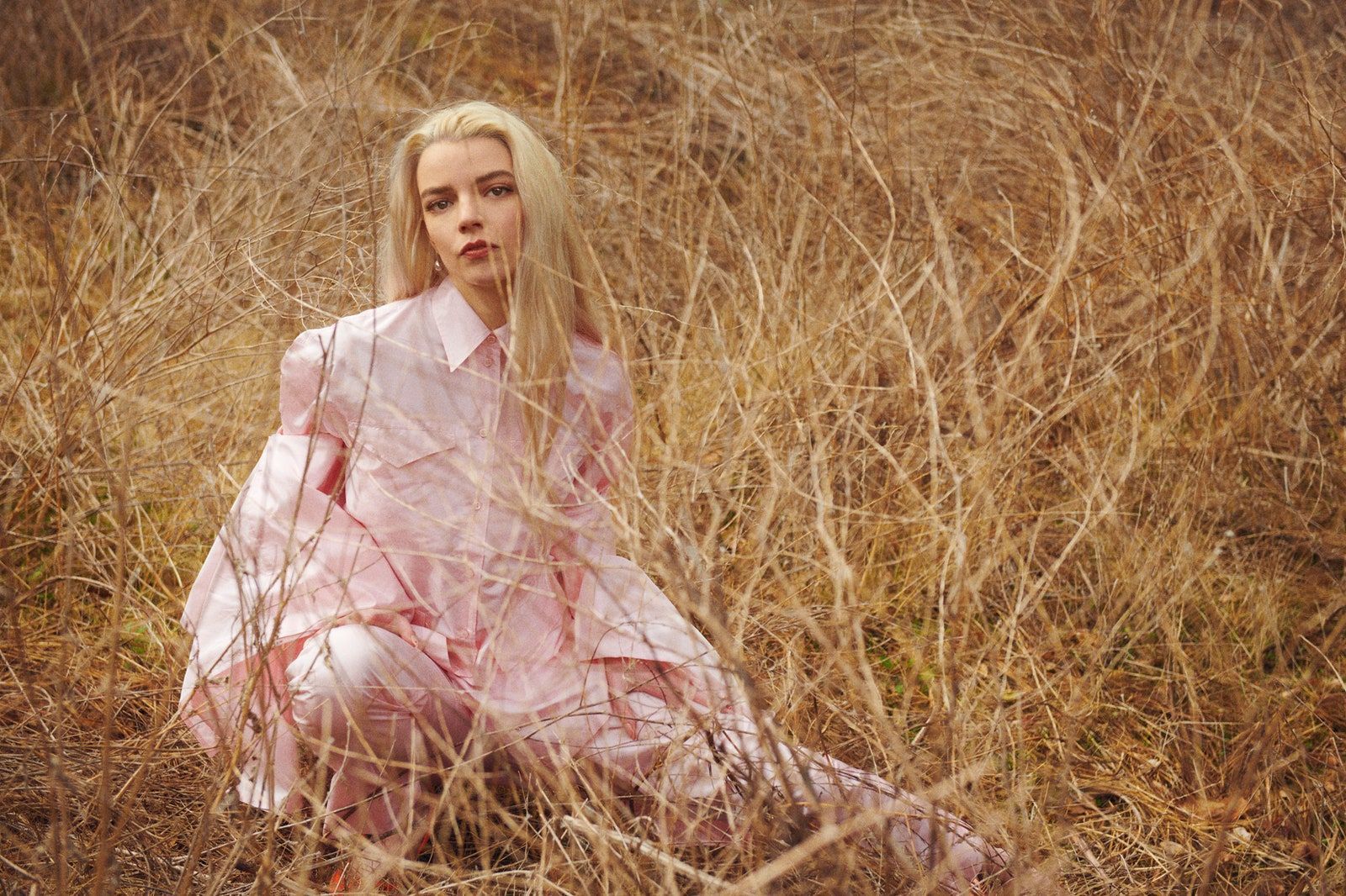 A woman in pink sitting on the ground - Anya Taylor-Joy