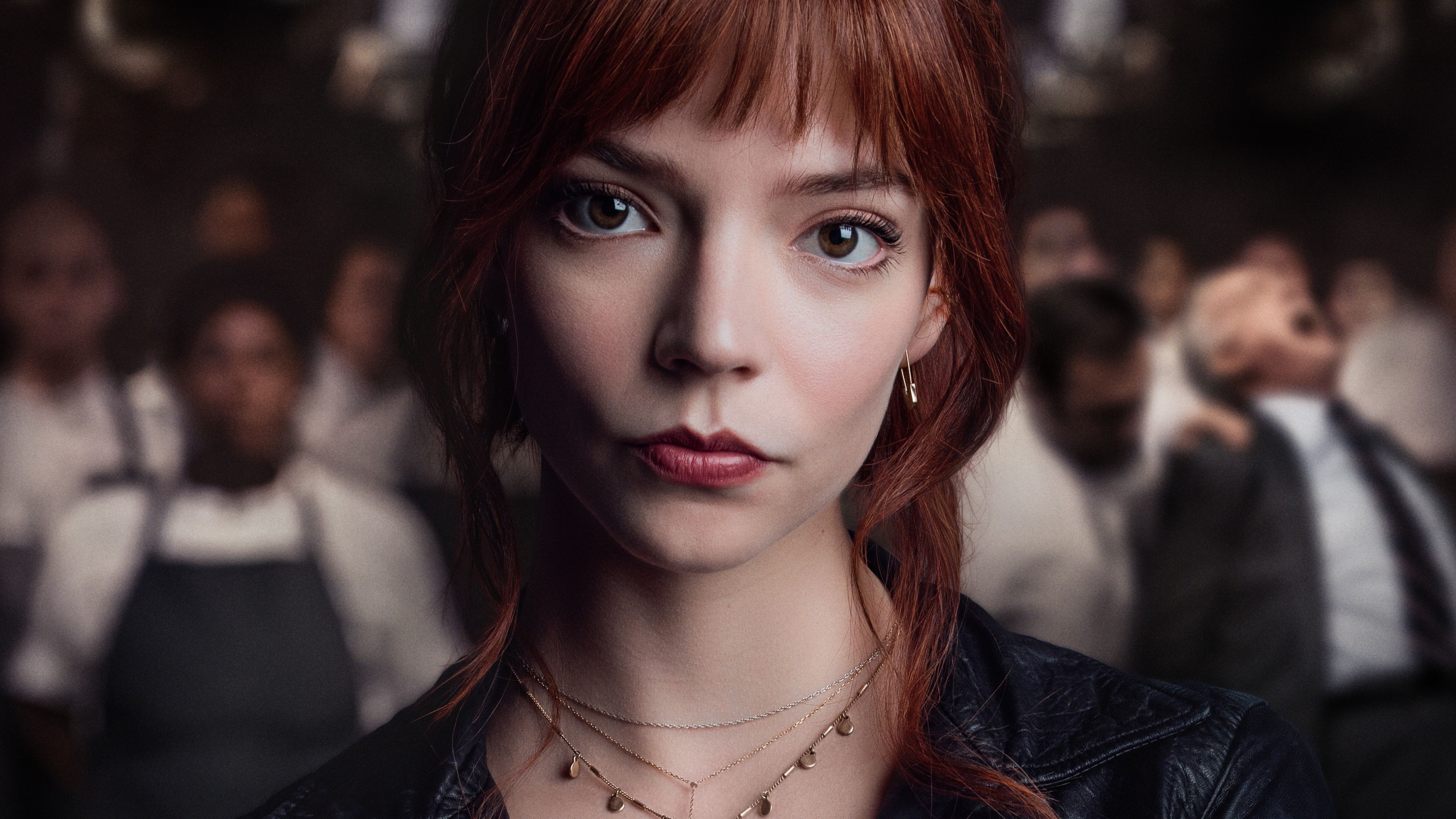 A woman with red hair and bangs looks directly into the camera. - Anya Taylor-Joy