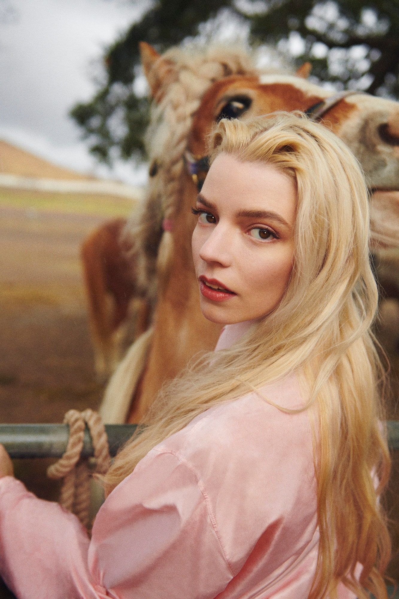 A woman is standing next to some horses - Anya Taylor-Joy