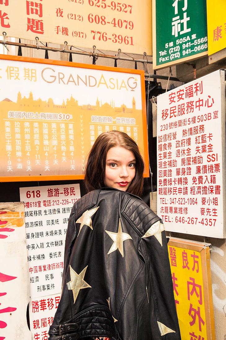 A woman standing in front of many signs - Anya Taylor-Joy