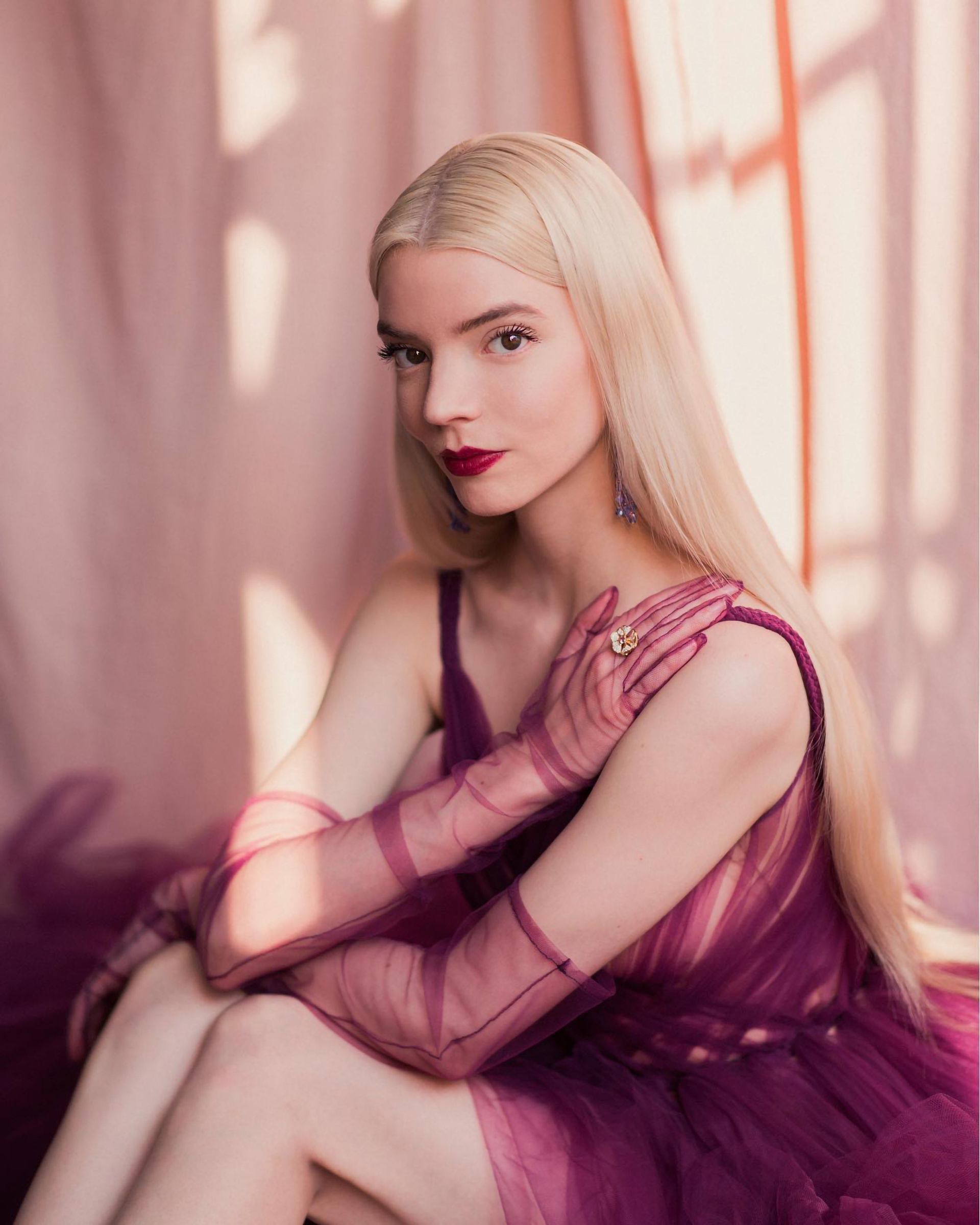 A blonde woman wearing a purple dress and gloves - Anya Taylor-Joy