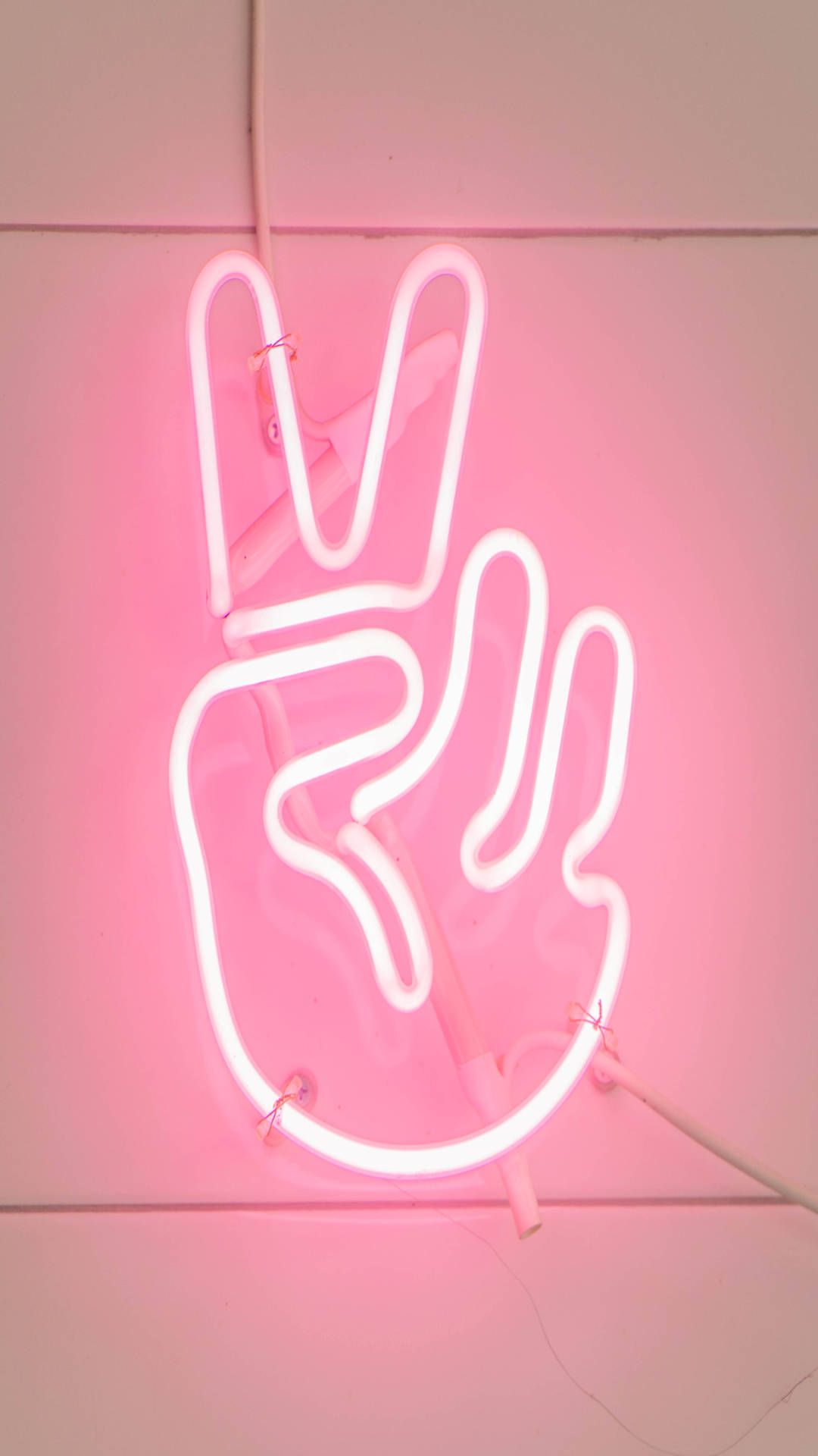 A pink neon sign with the peace symbol - Peace