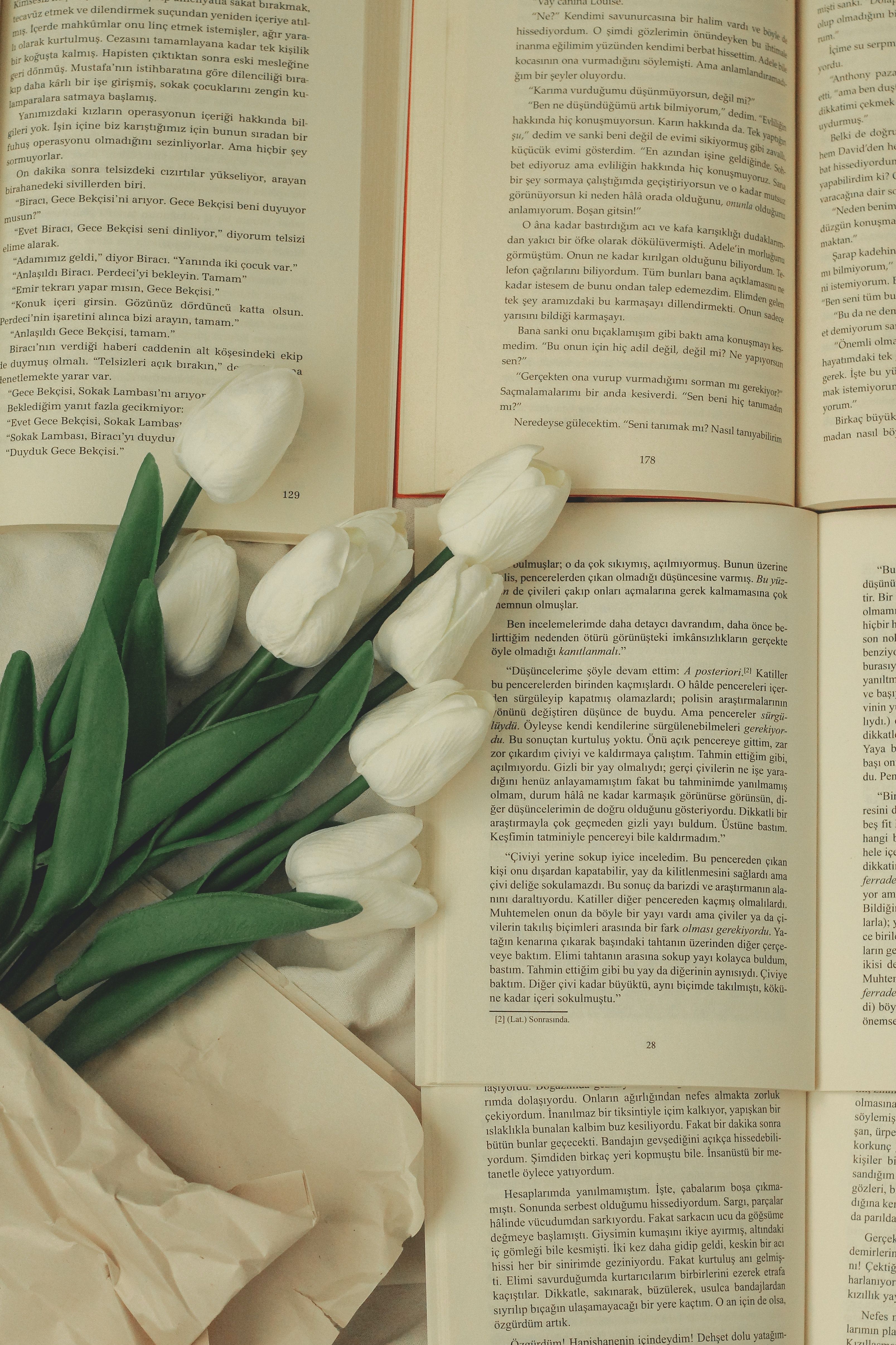 A book is open on a table with a bouquet of white tulips. - Tulip, books