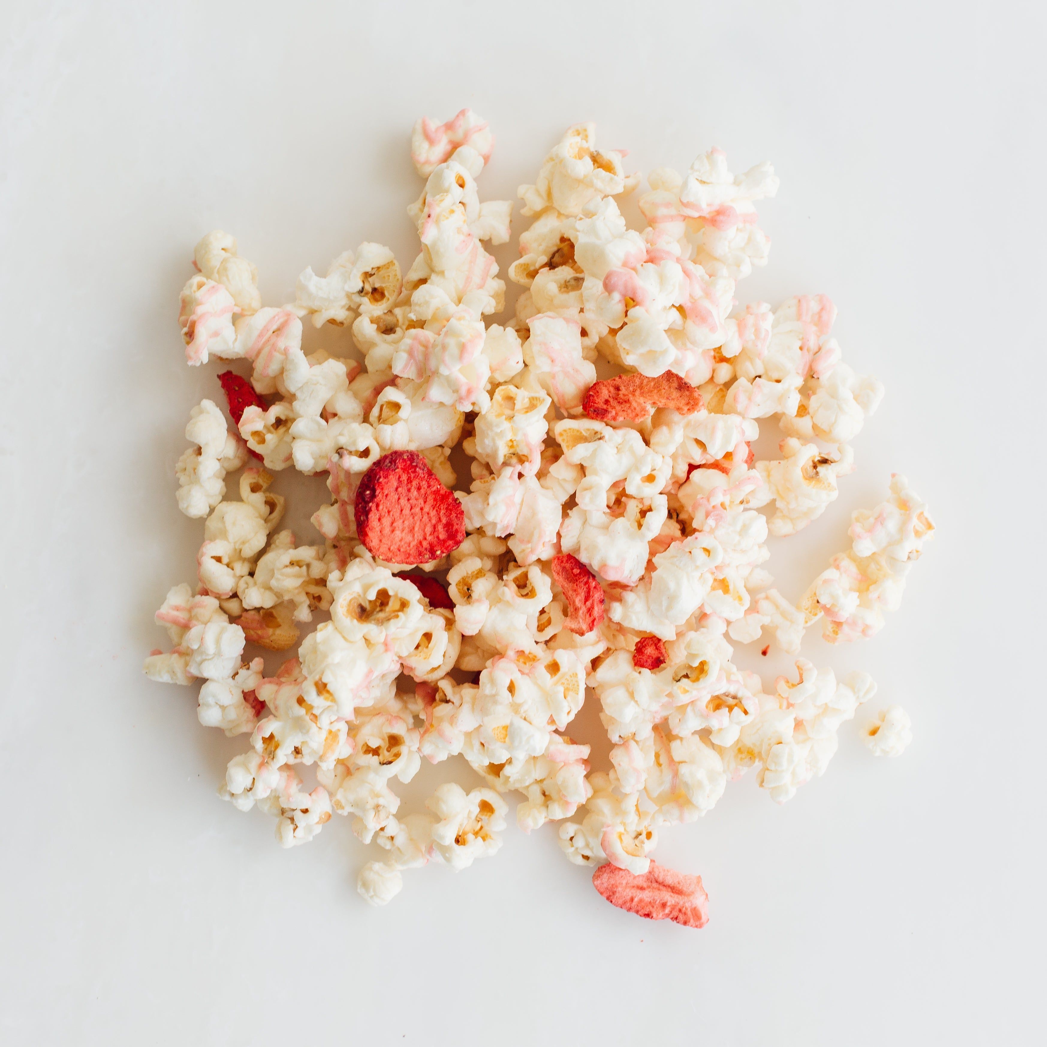 A pile of popcorn with a few strawberry pieces mixed in. - Popcorn