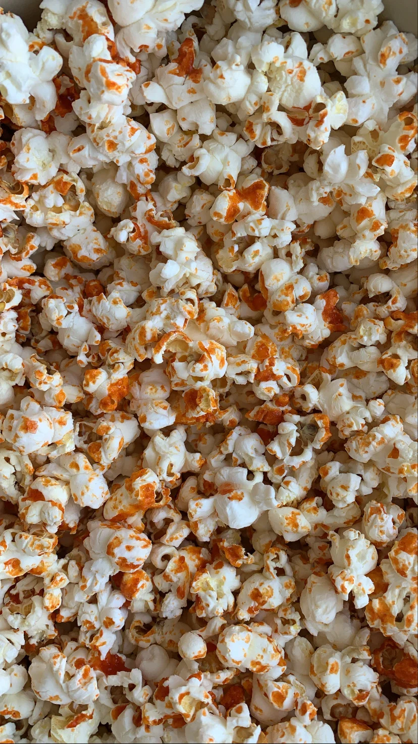 A close up of popcorn with orange and white kernels - Popcorn