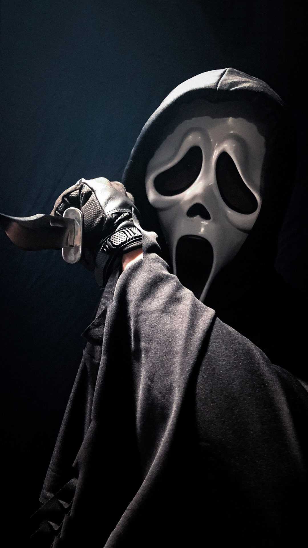 A person in costume holding up an object - Ghostface