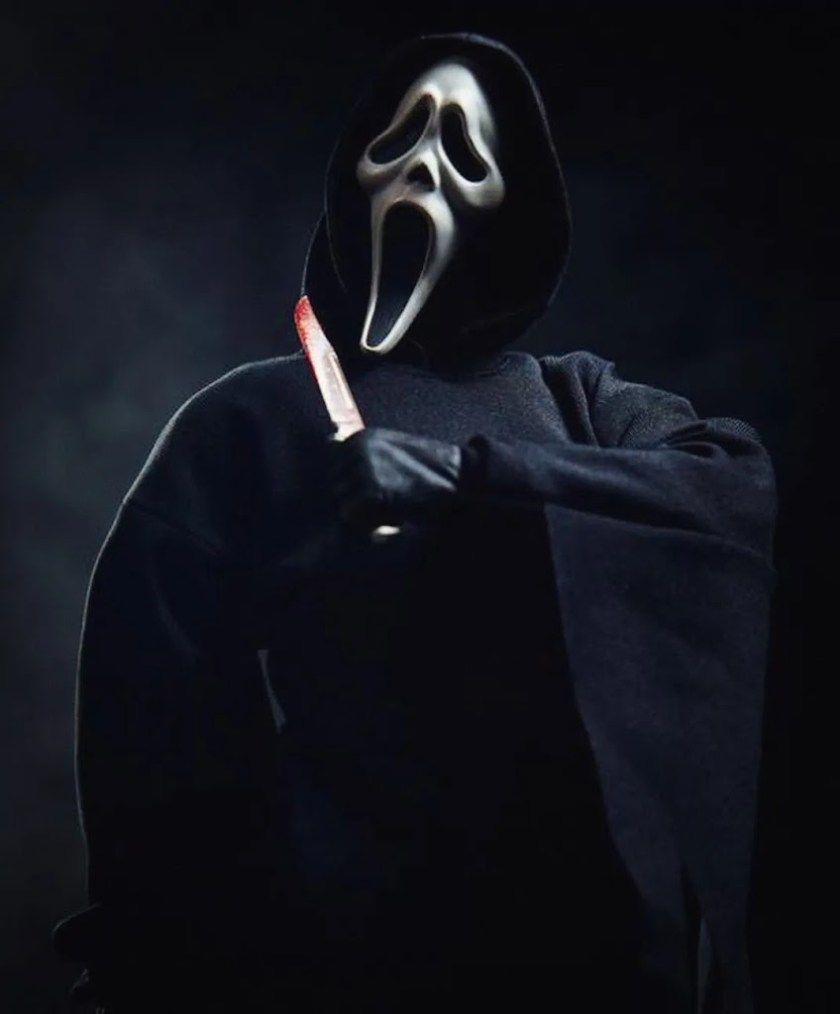 A person in costume holding up an ax - Ghostface