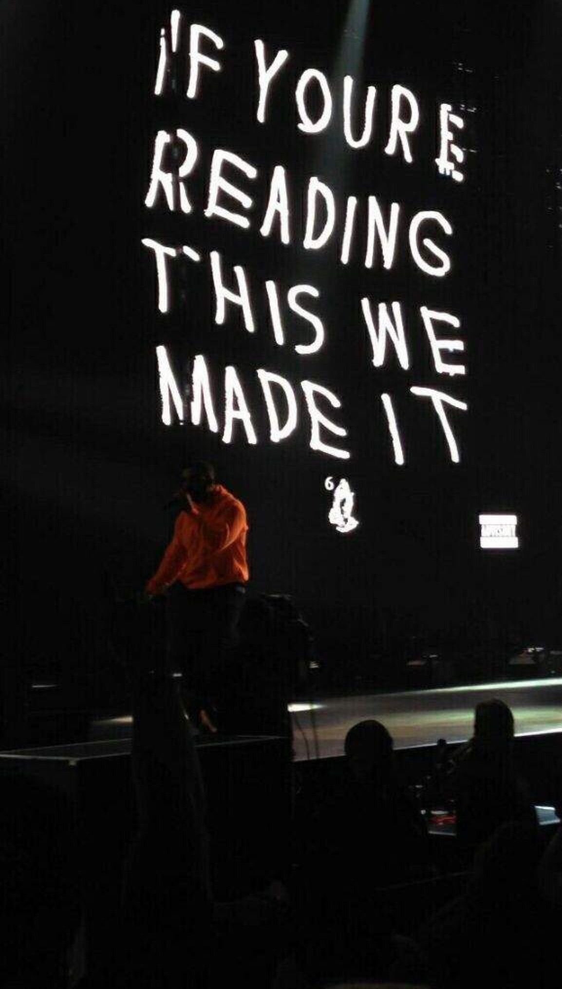A man is standing on stage with his back to the audience - Drake