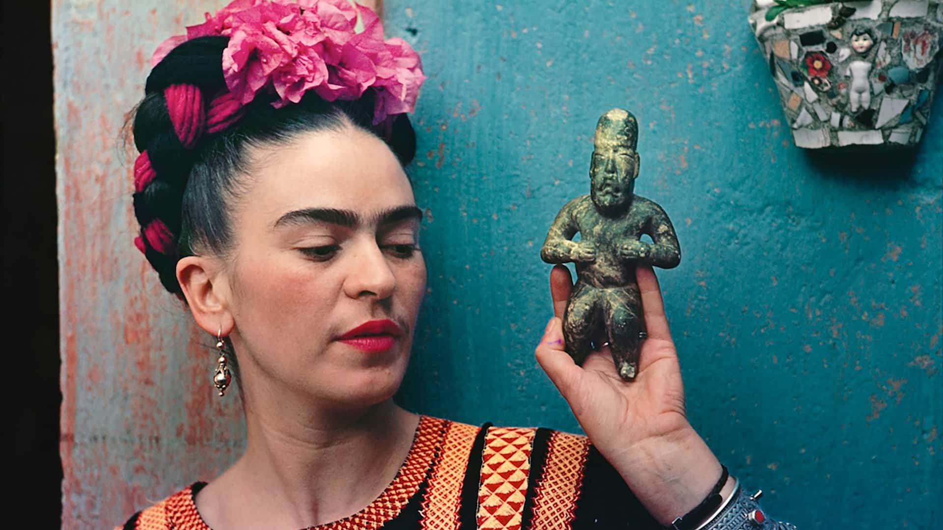A woman holding up an object in front of her face - Frida Kahlo
