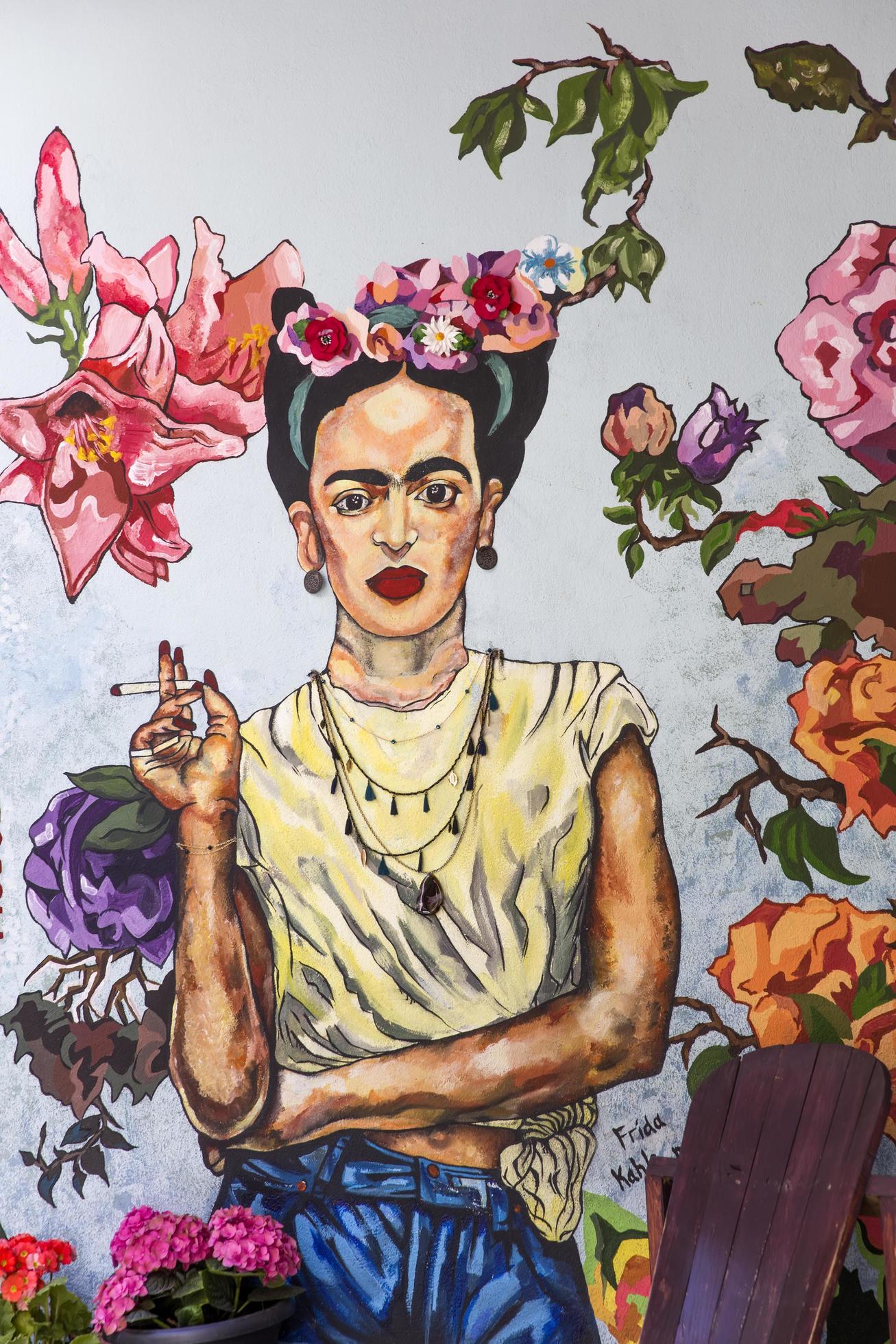A painting of frida kahlo is on the wall - Frida Kahlo