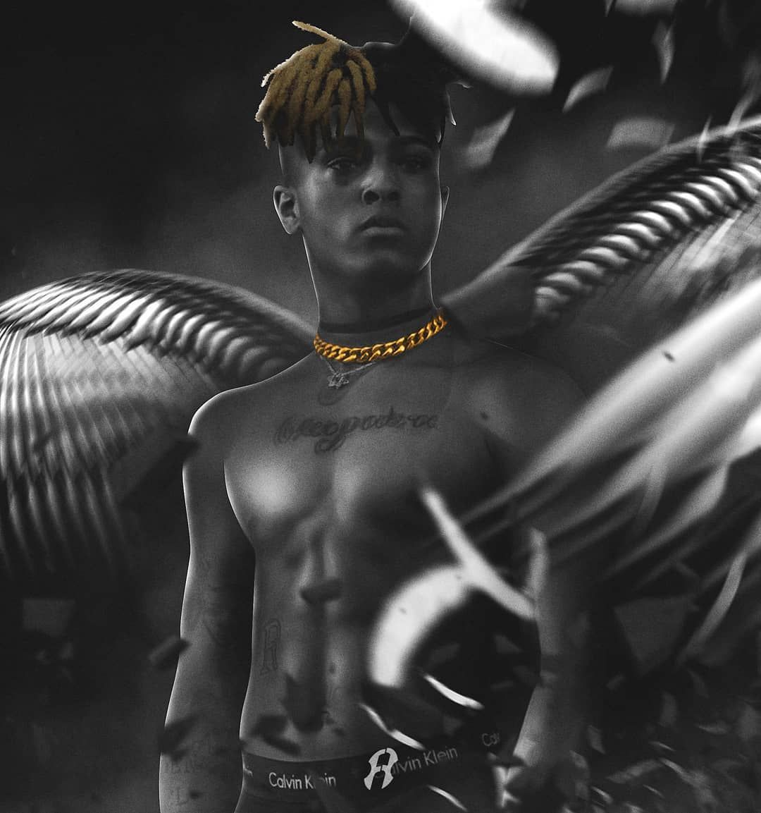 A black and white photo of a shirtless man with yellow hair and a gold chain around his neck. - XXXTentacion