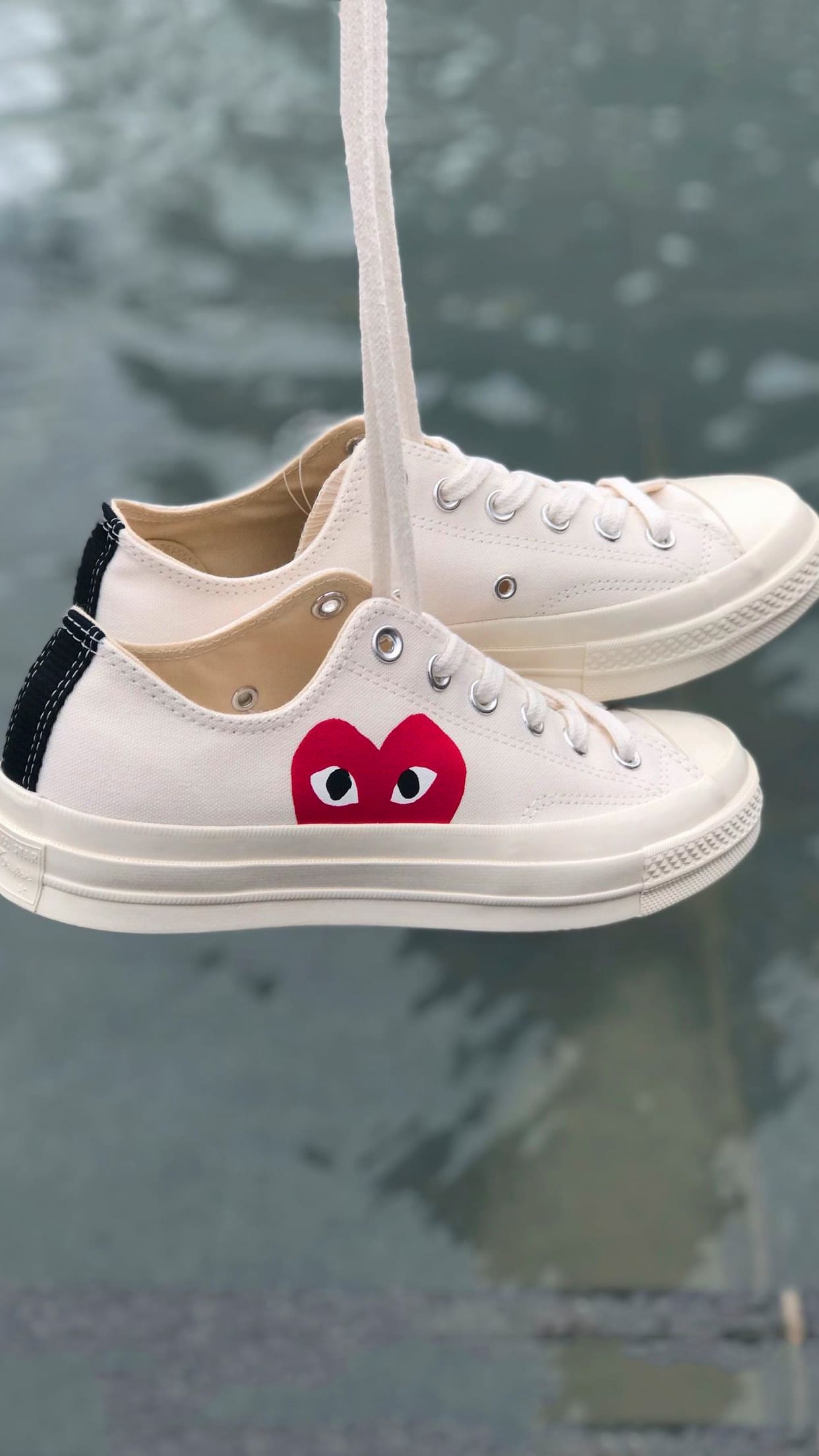 A pair of white sneakers with a red heart on them. - Converse