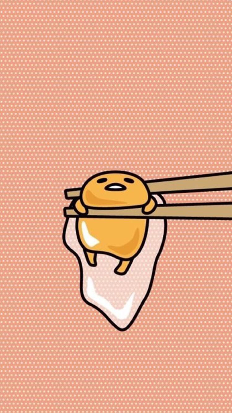 A hand holding a yellow egg with chopsticks on top - Gudetama