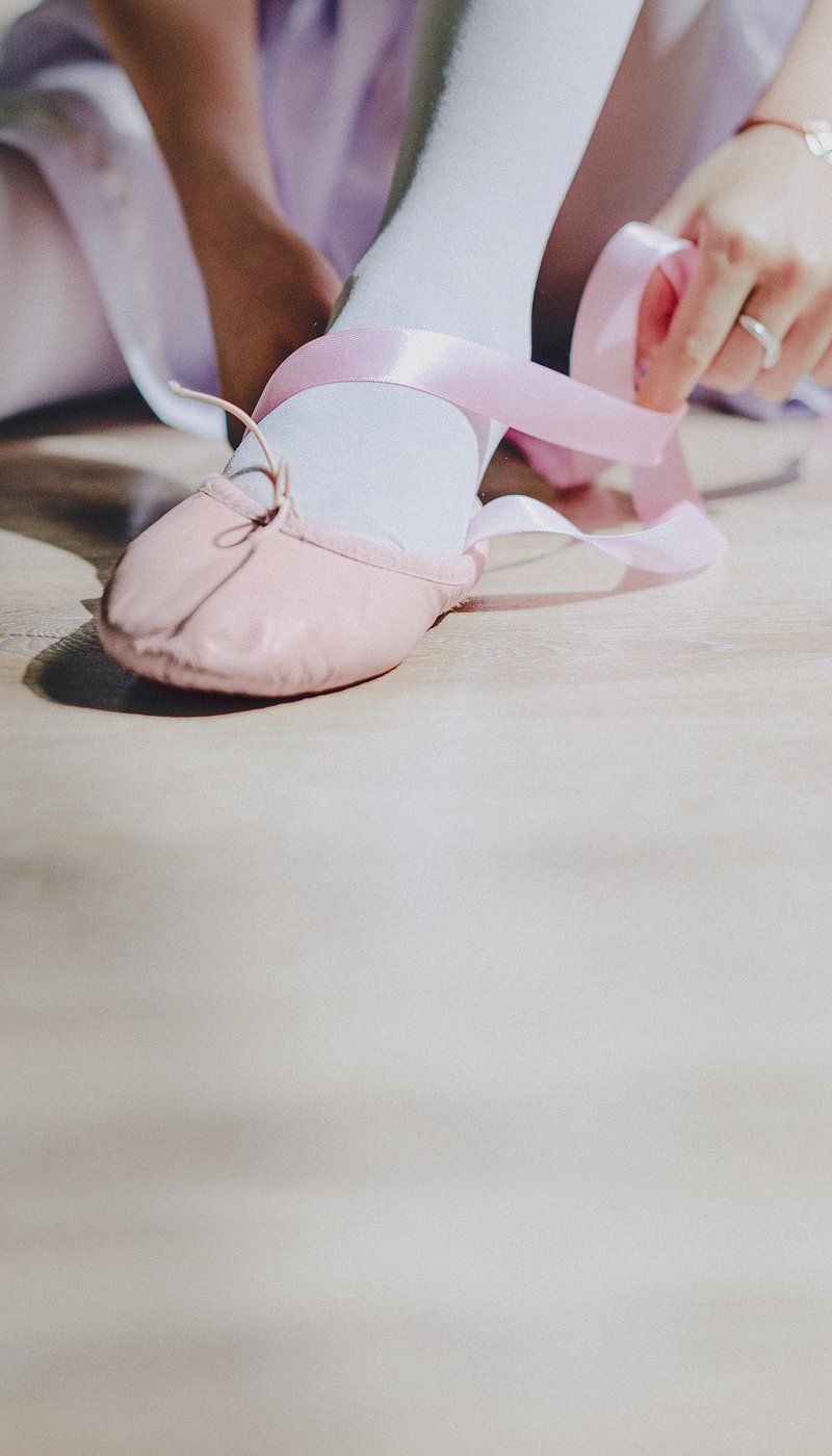 A young ballerina ties her pink ballet shoes - Ballet