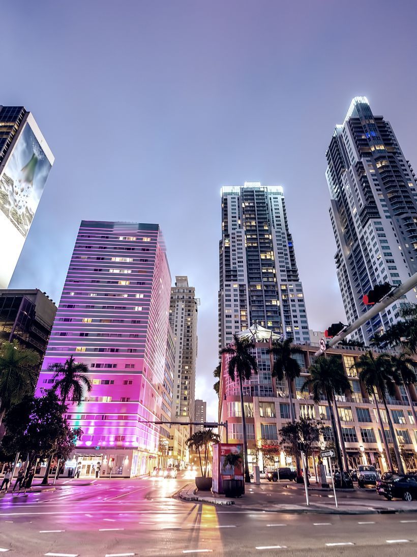 A city street with tall buildings lit up at night - Miami