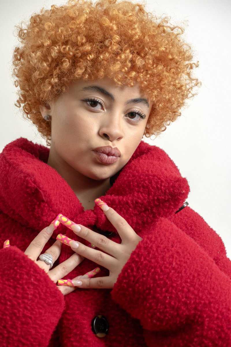 A woman with red curly hair and a red coat - Ice Spice