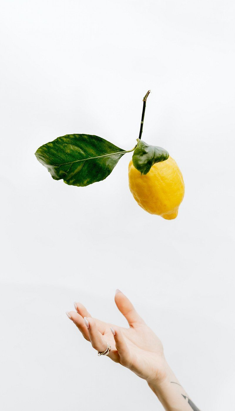 A person is holding up an orange - Lemon