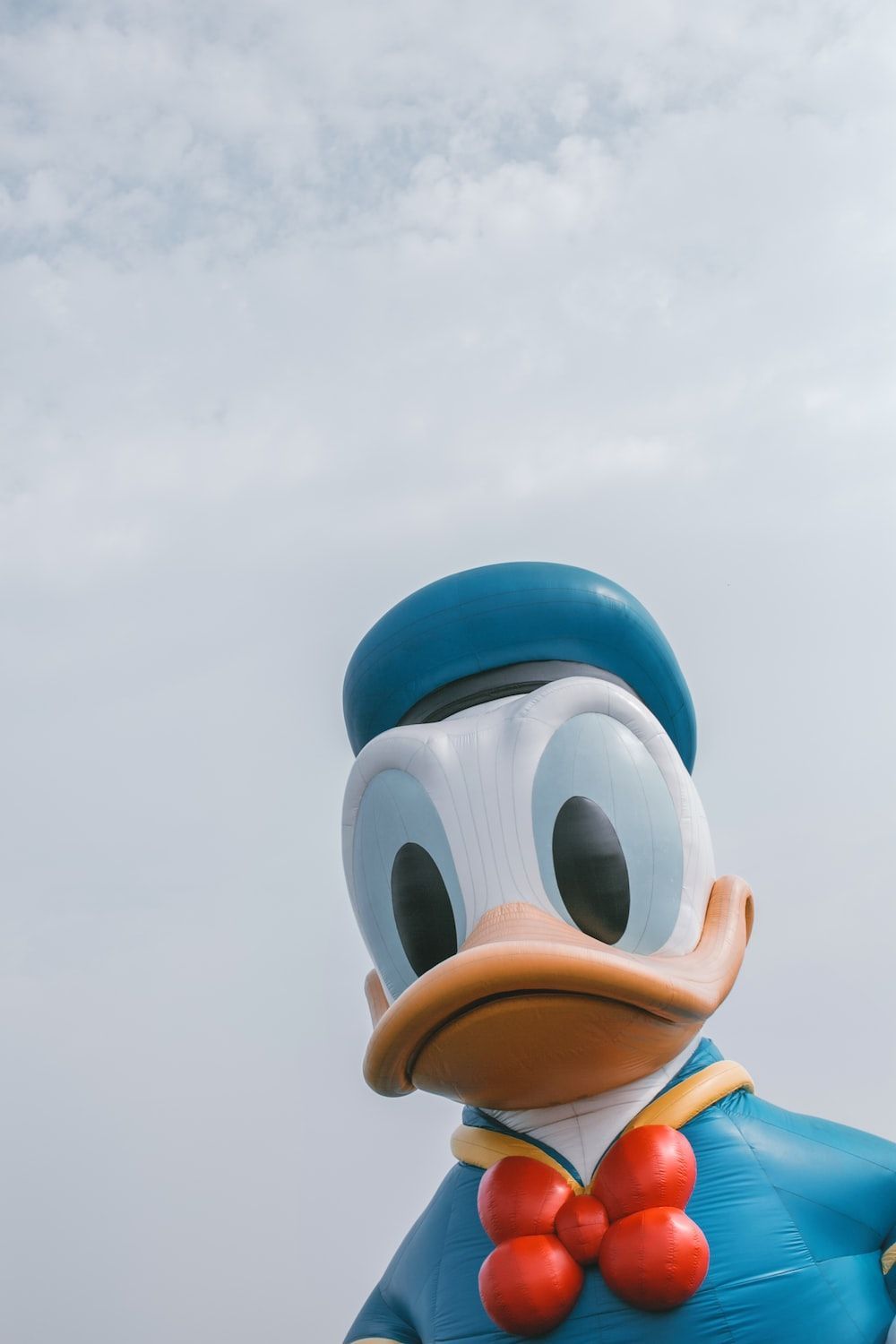 A large duck with a bow tie standing in front of a cloudy sky photo