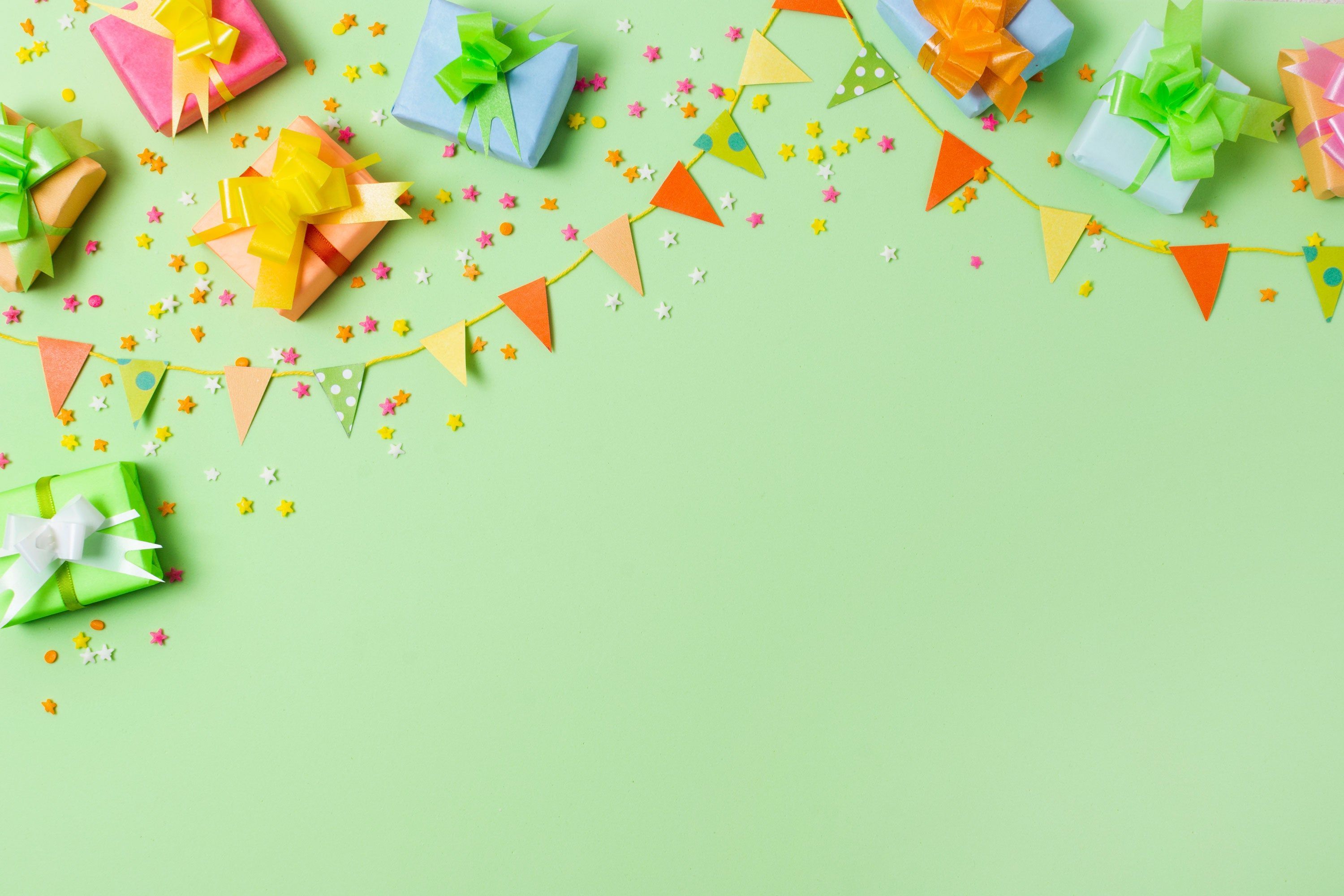 A green background with colorful gift boxes and confetti. - Birthday