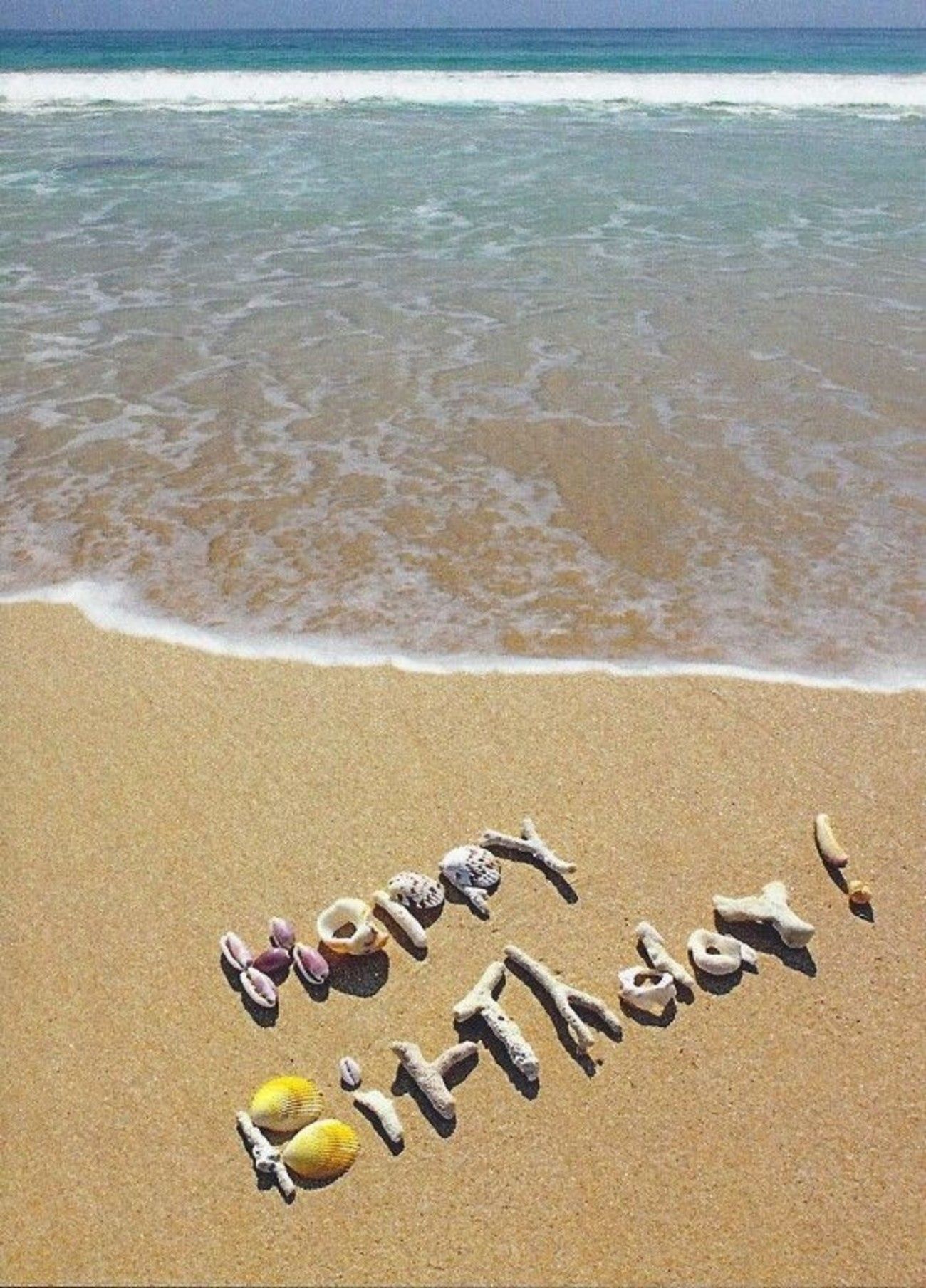 A happy birthday message written in the sand on top of beach - Birthday