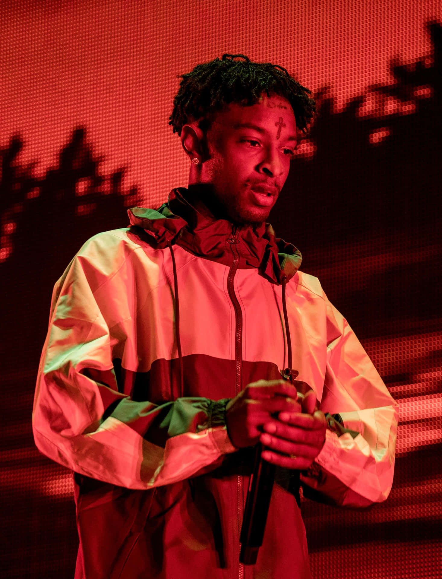 A man in an orange jacket is holding something - 21 Savage