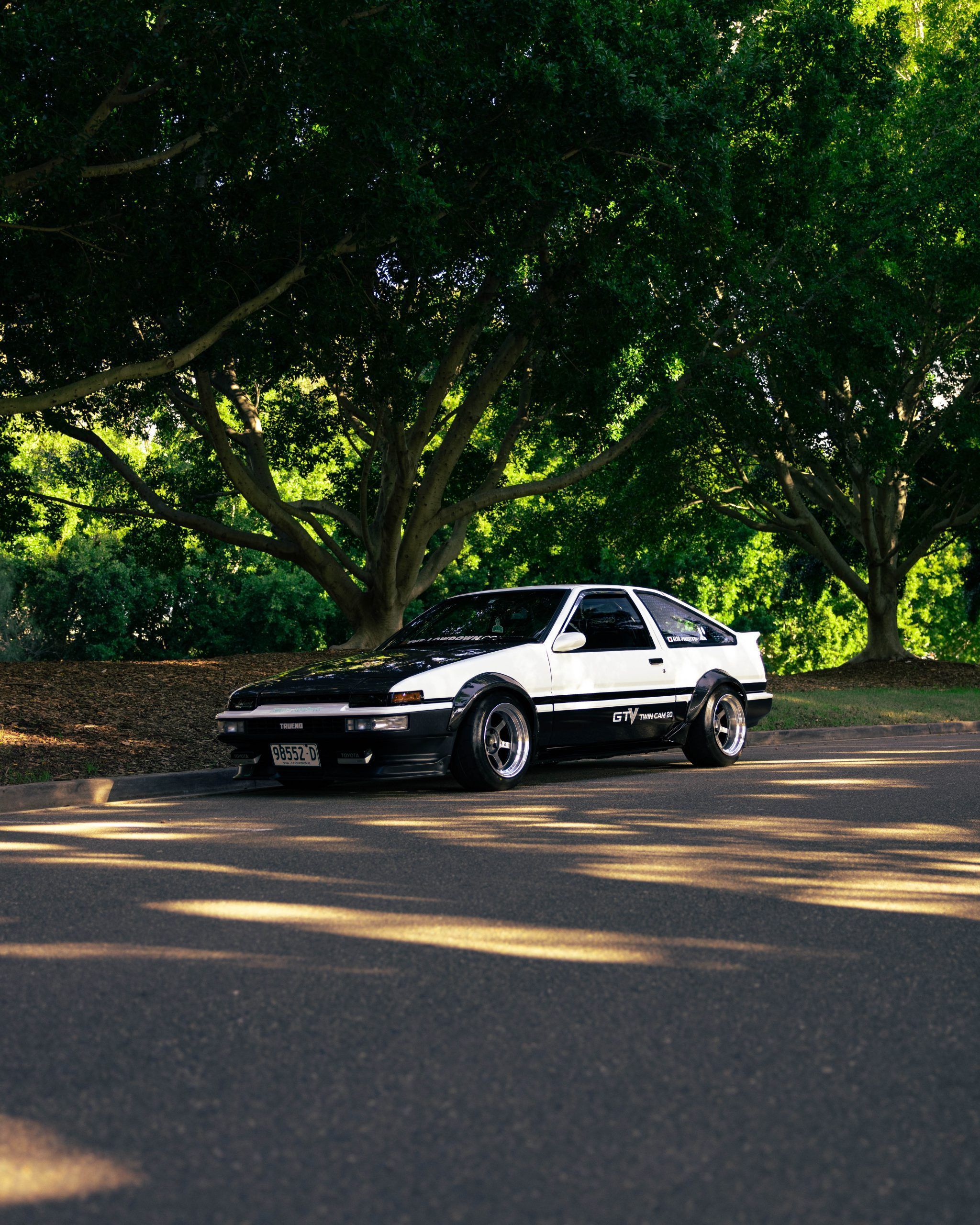 A car is parked on the side of an empty road - Toyota AE86