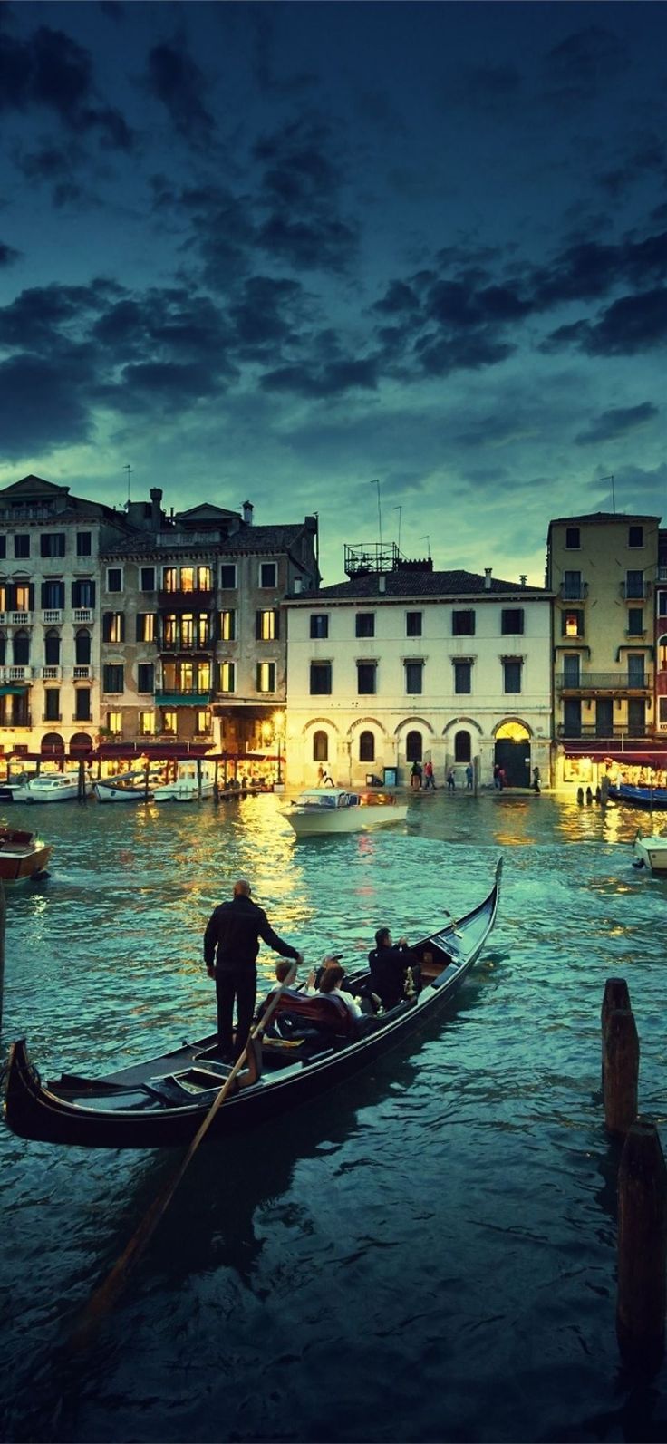 A gondola glides through the water at night in Venice, Italy. - Italy