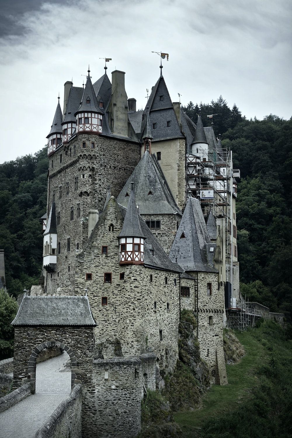 A castle on a hillside with turrets and a bridge leading to it. - Castle