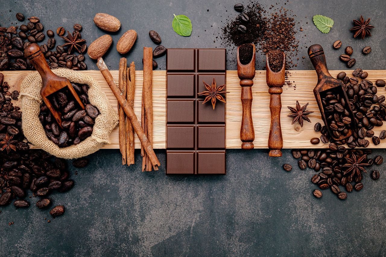 A bar of chocolate surrounded by coffee beans, spices and other ingredients - Flat lay, coffee, chocolate