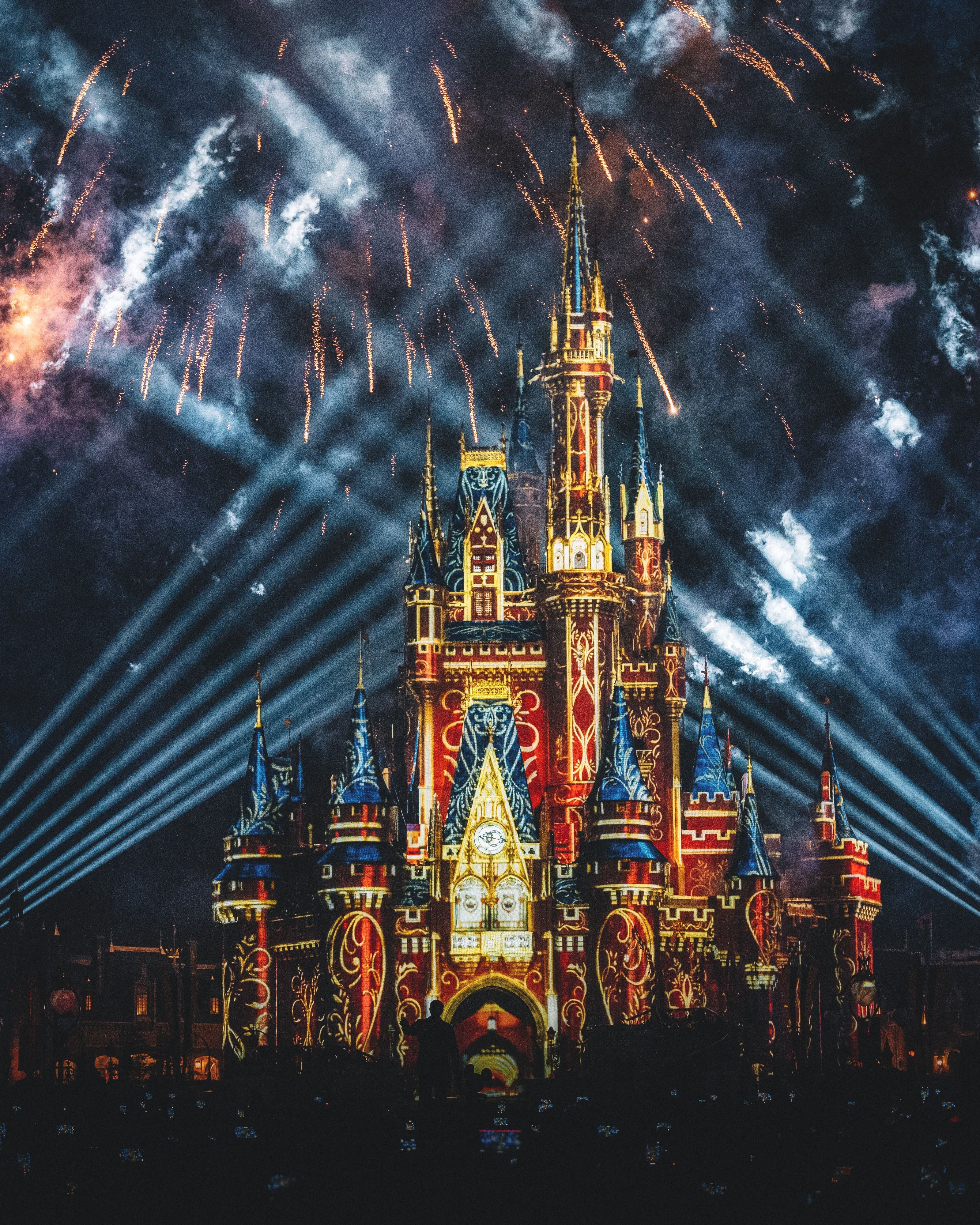 Fireworks light up the sky behind the lit-up castle at Disney World. - Castle